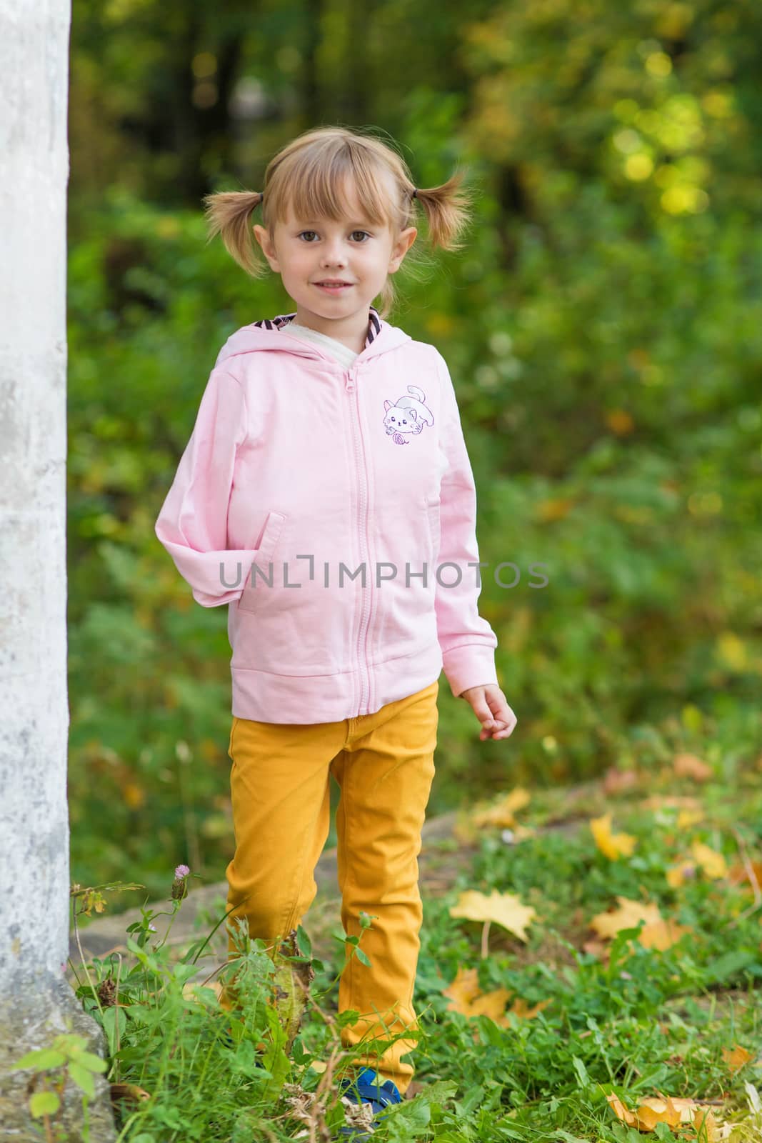 .A girl with a broken arm stands near a column in an old park on an autumn walk