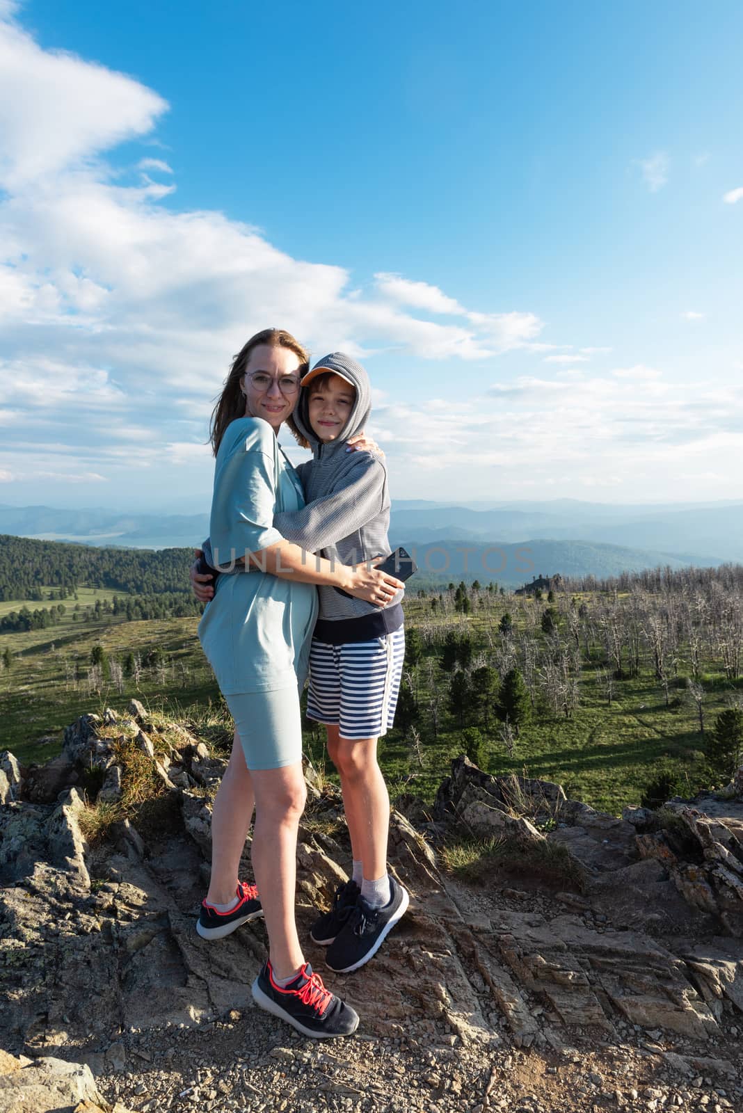 A child embraces mom in the mountain trip. Domestic tourism, travel, lesure and freedom. Altai mountain, beauty summer evening landcape