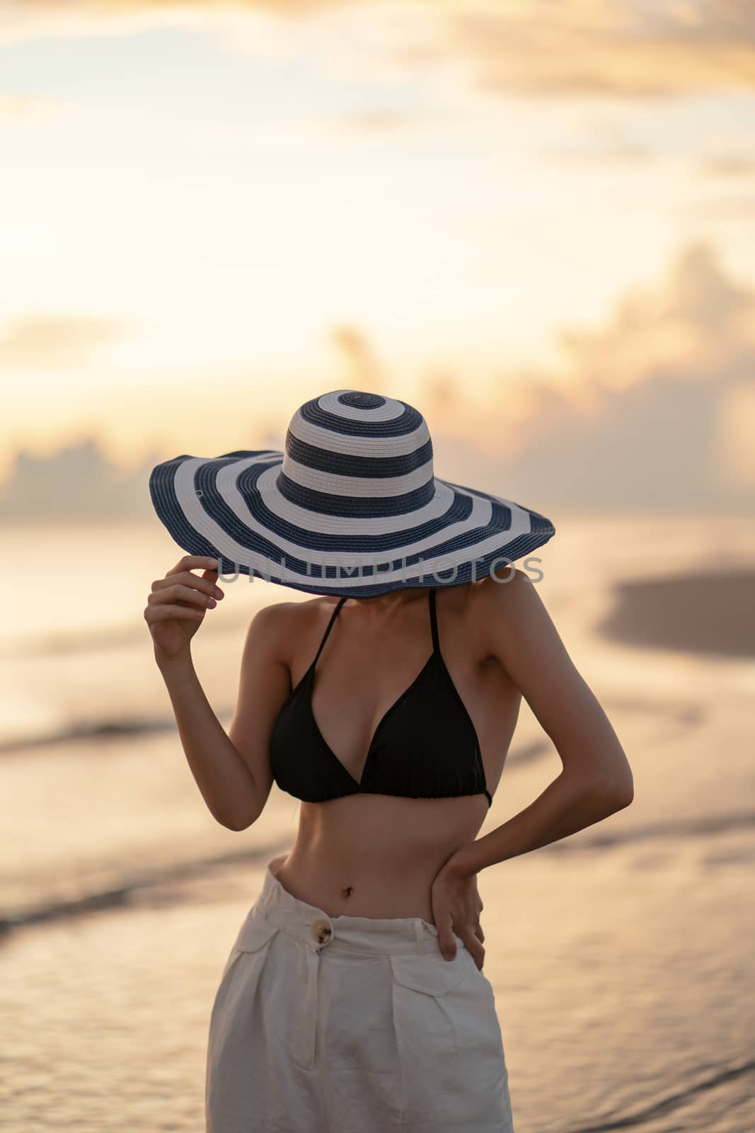 Woman in top bikini and white long pant wearing hat (Focus Hat)