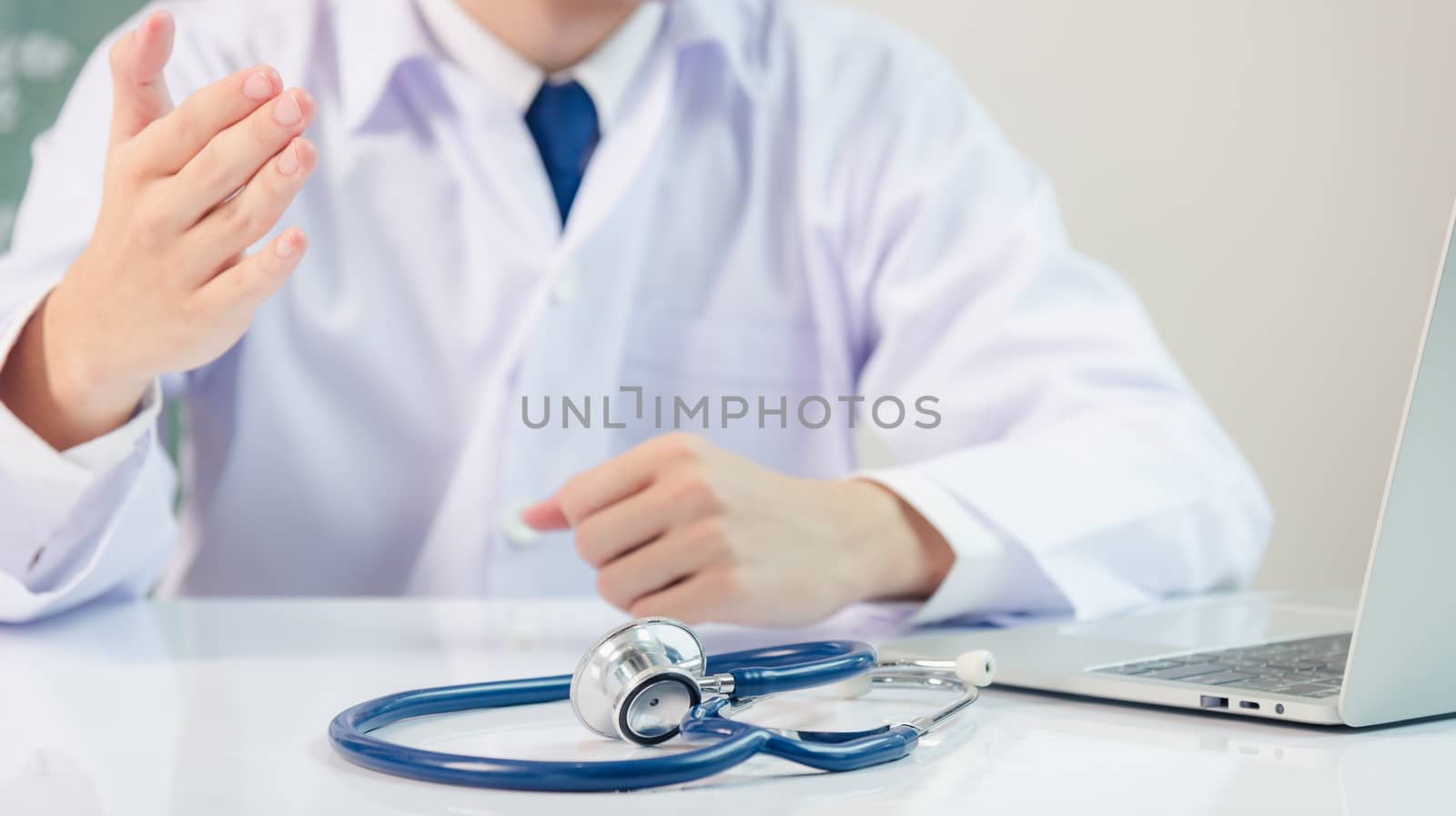 Medicine doctor's working on desk. Closeup of Stethoscope. Physician man video call raise hands explain patient understand on table front computer monitor at hospital office, Healthcare medic concept