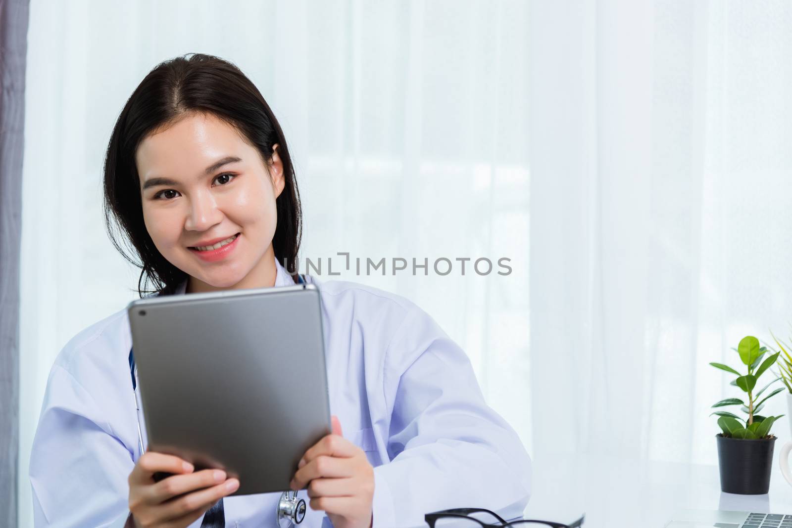 Woman doctor on front laptop computer hold modern tablet by Sorapop