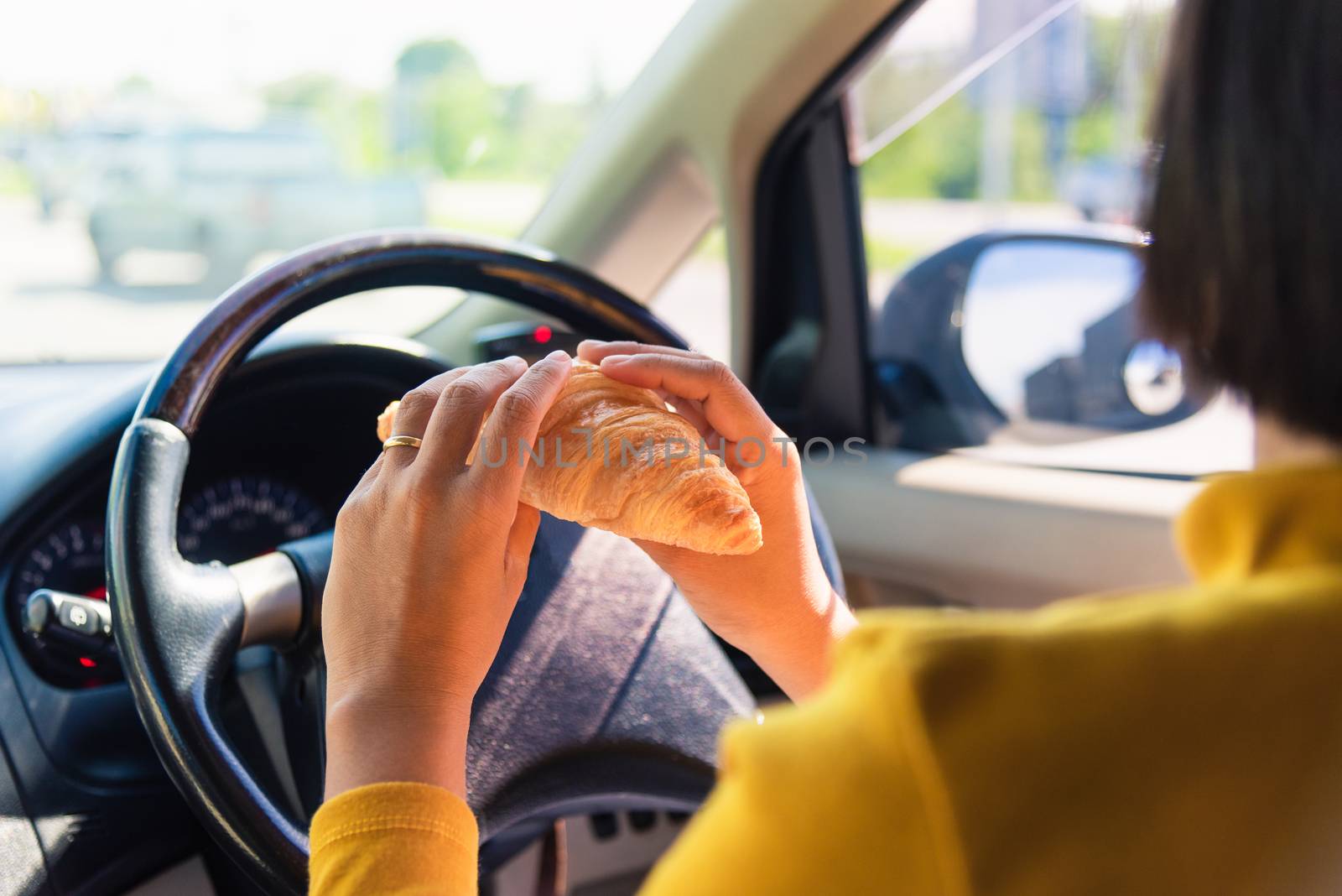 Asian woman eating food fastfood while driving the car in the morning during going to work on highway road, Transportation and vehicle concept