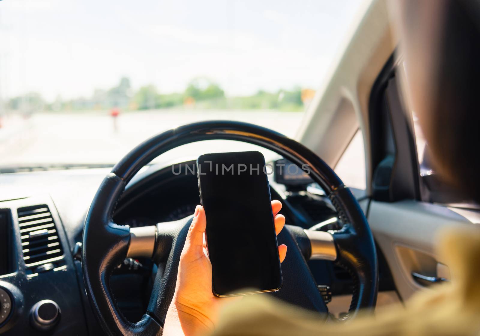 woman inside a car and using a hand holding mobile smartphone by Sorapop