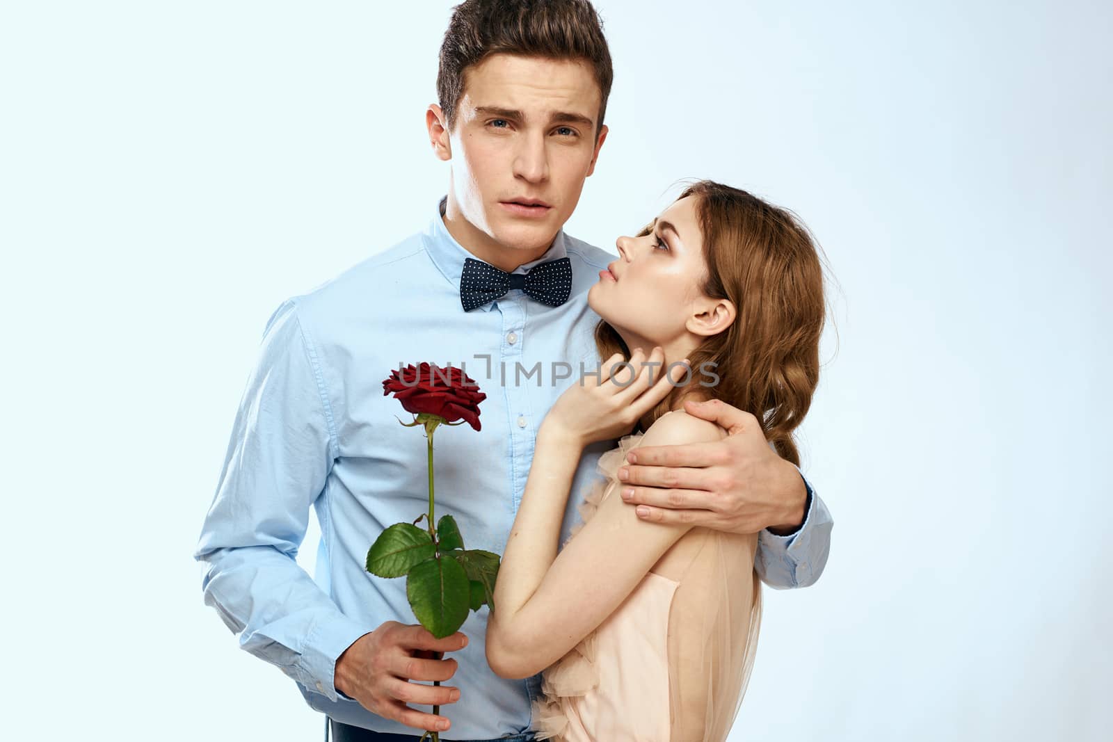 Man and woman with a red rose on a light background love family hugs by SHOTPRIME