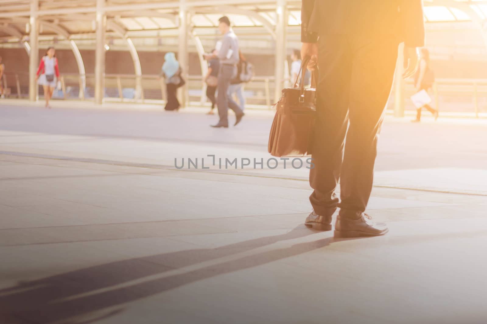 Young man walking carrying leather bag at sunset.