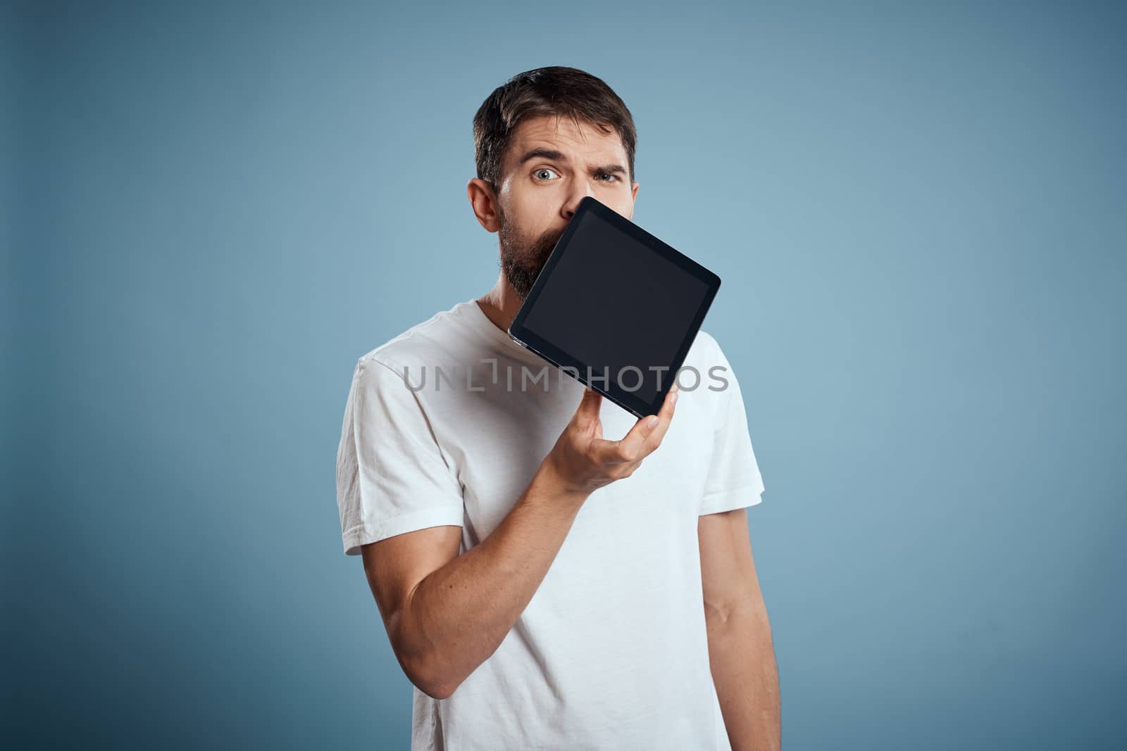 A guy with a tablet on a blue background and in a white T-shirt sensor Monitor Model. High quality photo