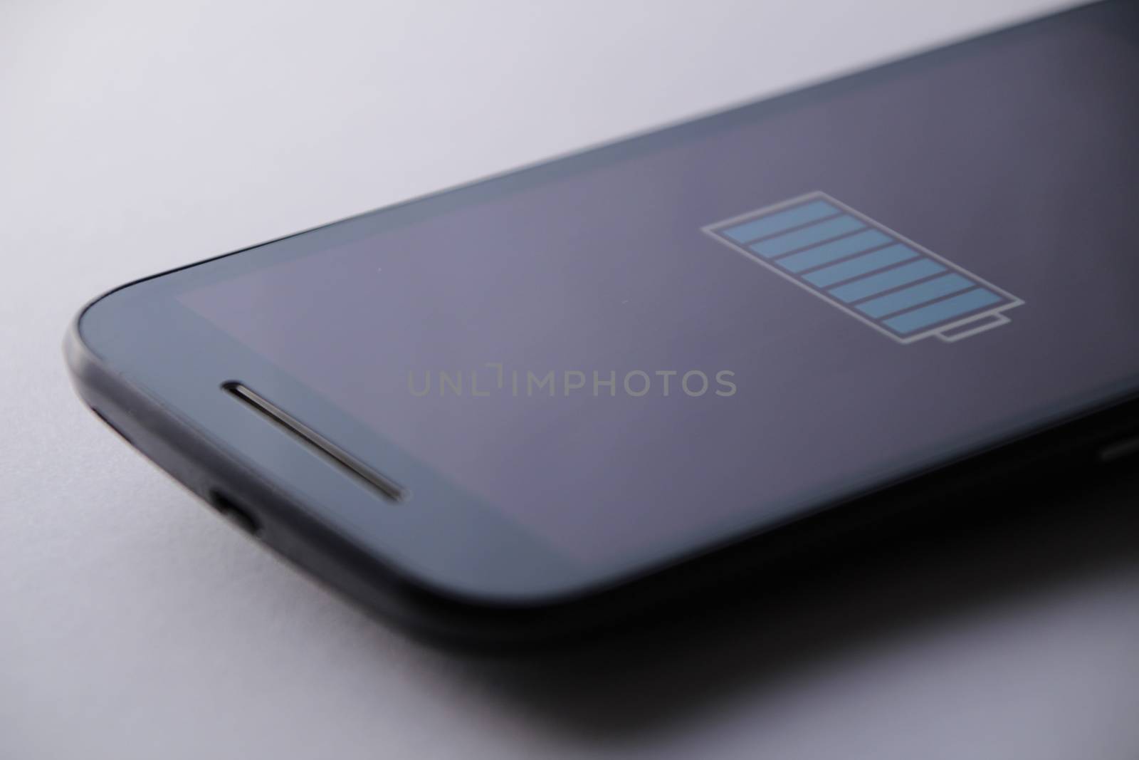 Smartphone charging battery with micro usb cable. White background.