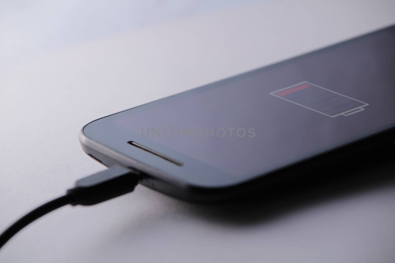 Smartphone charging battery with micro usb cable. White background.