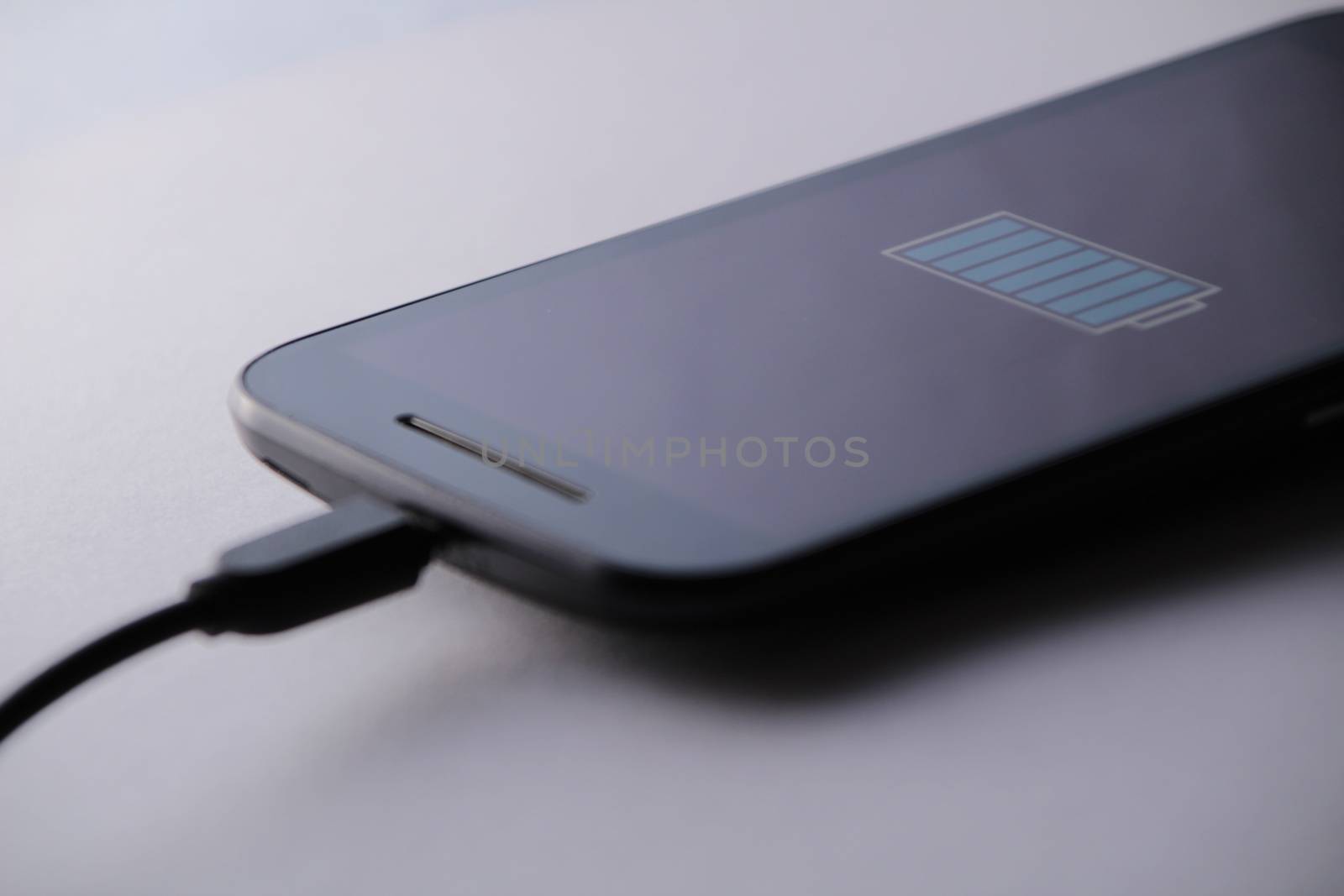 Smartphone charging battery with micro usb cable. White background.