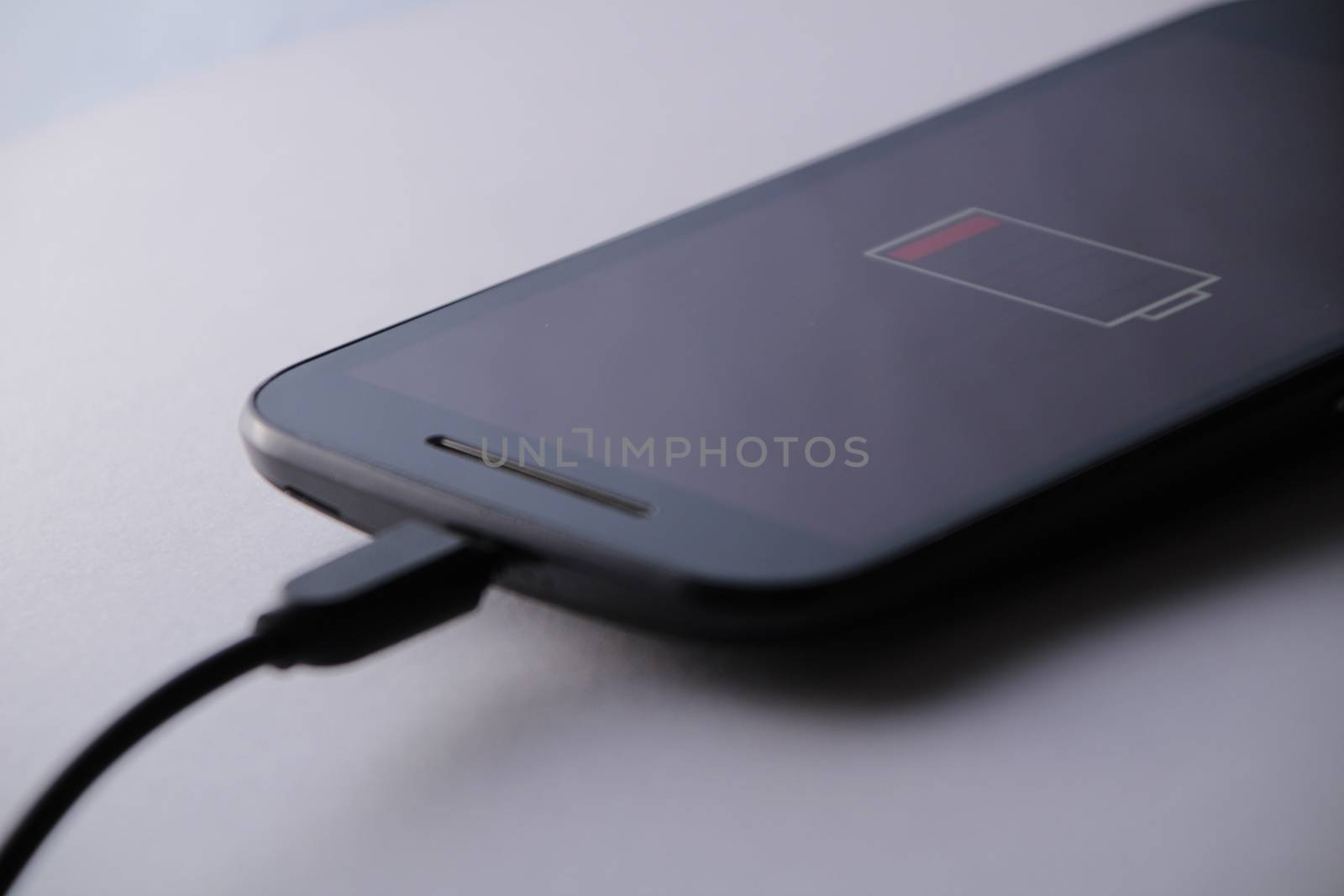 Smartphone charging battery with micro usb cable. White background.
