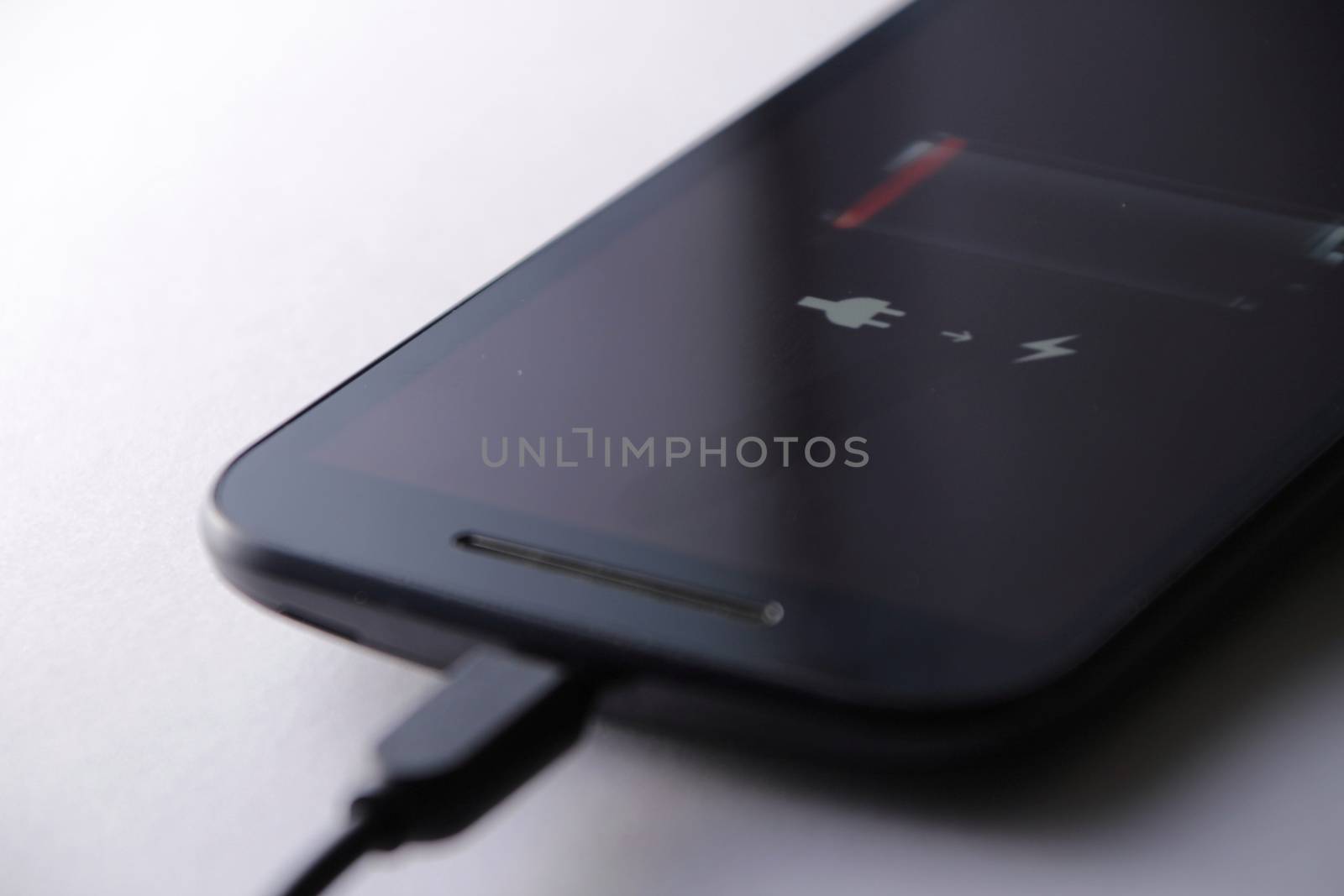 Smartphone charging battery with micro usb cable. White background.