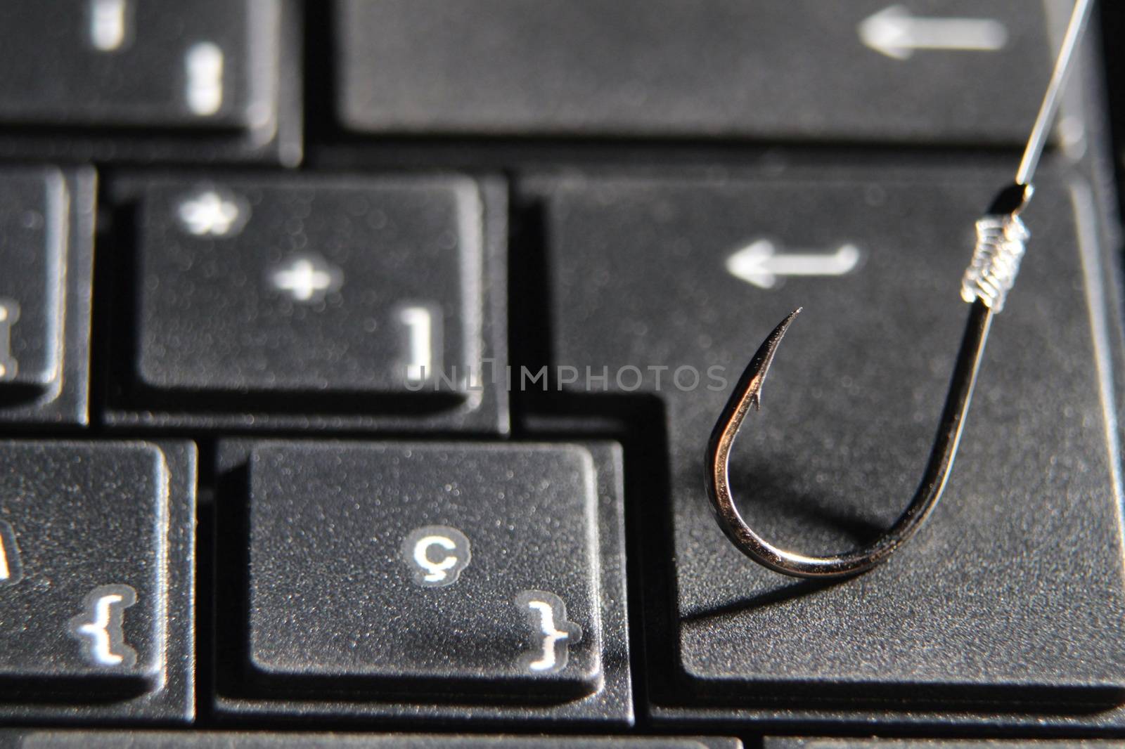 Conceptual picture of a hook on laptop keyboard suggesting cyber fraud and phishing