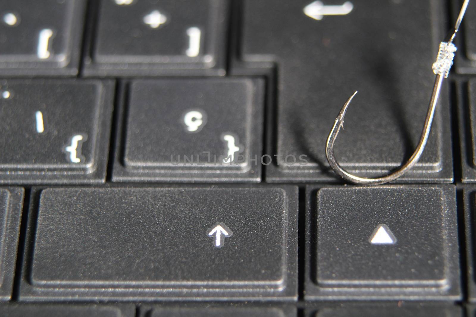 Conceptual picture of a hook on laptop keyboard suggesting cyber fraud and phishing