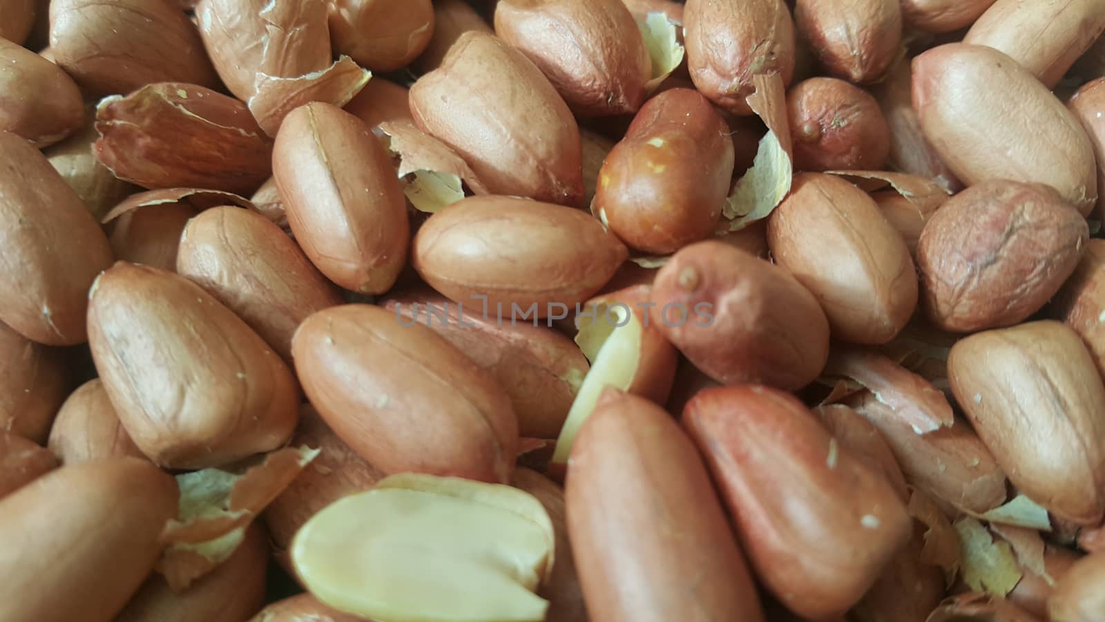 Closeup view of mixed, dried, roasted  peeled and unpeeled peanuts. A fruit for background text