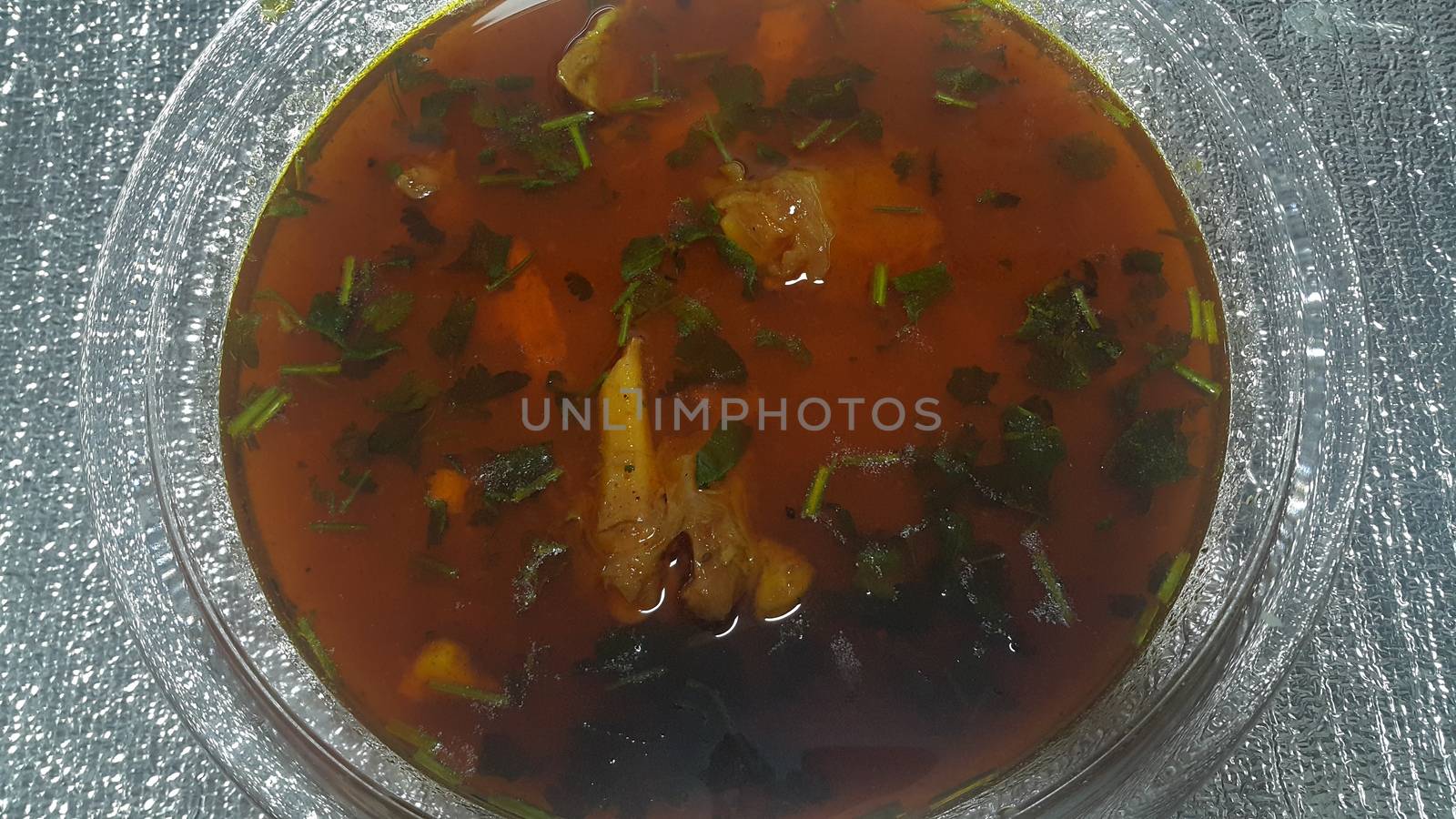 Top view of siri paaye or paya dish garnished with diced ginger, long coriander leaves and fresh sliced lemon. This dish is popular in Pakistan and Bangladesh