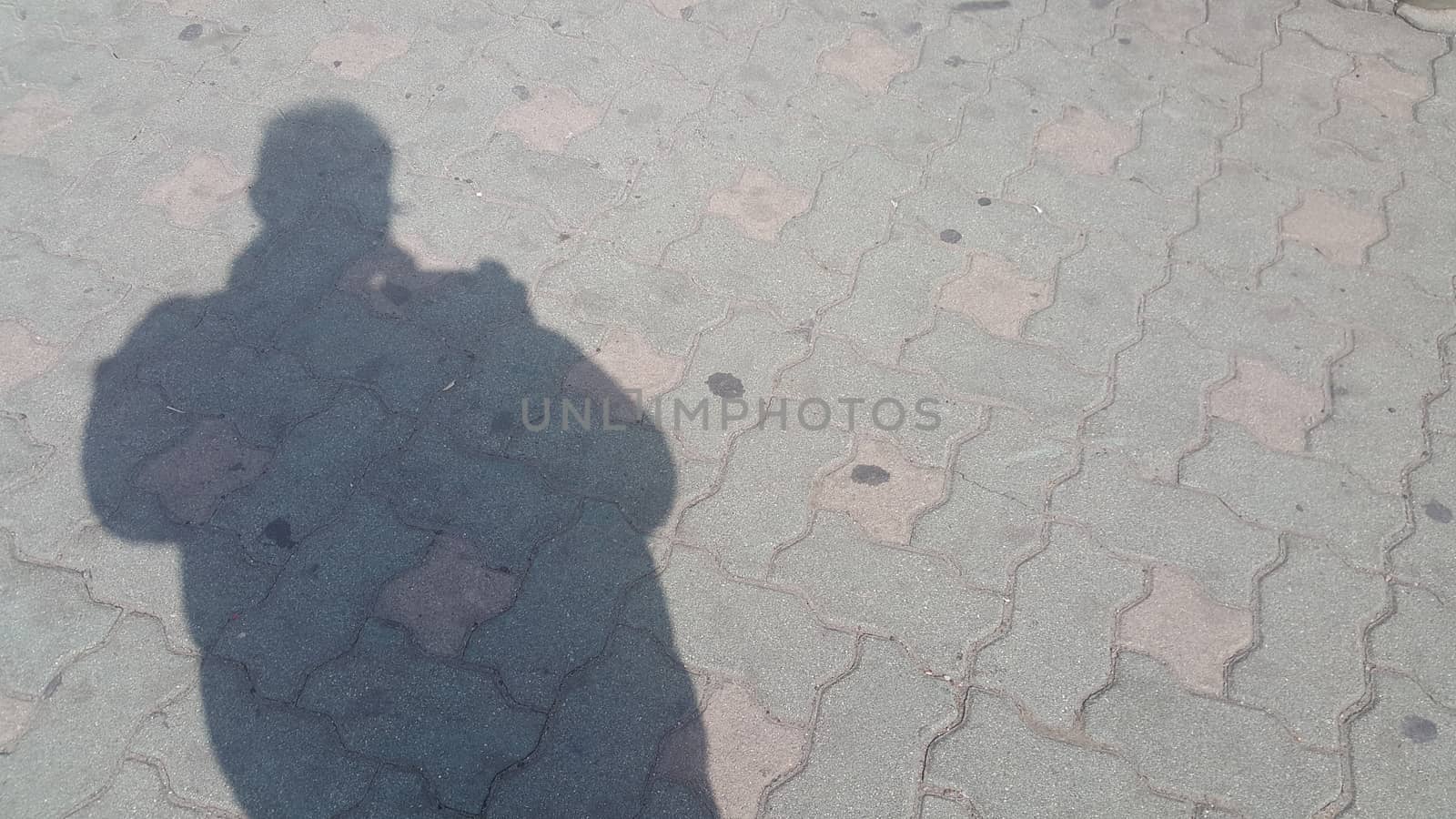 Silhouette: A Man's shadow on the red colored concrete ground under sunlight