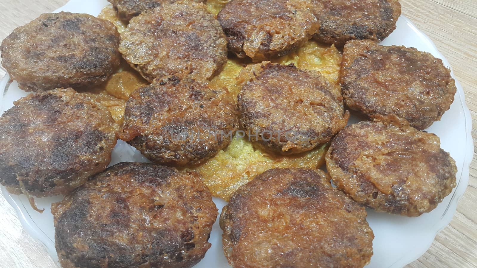 Delicious spicy fried round kebab served in a white ceramic plate on wooden floor, Asian recipe