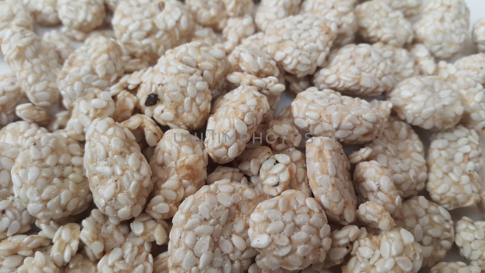 Closeup view of home made Asian sweet food called rewri or rewdi oe sesame seed sweet mad with jaggey and served in a white plate. 