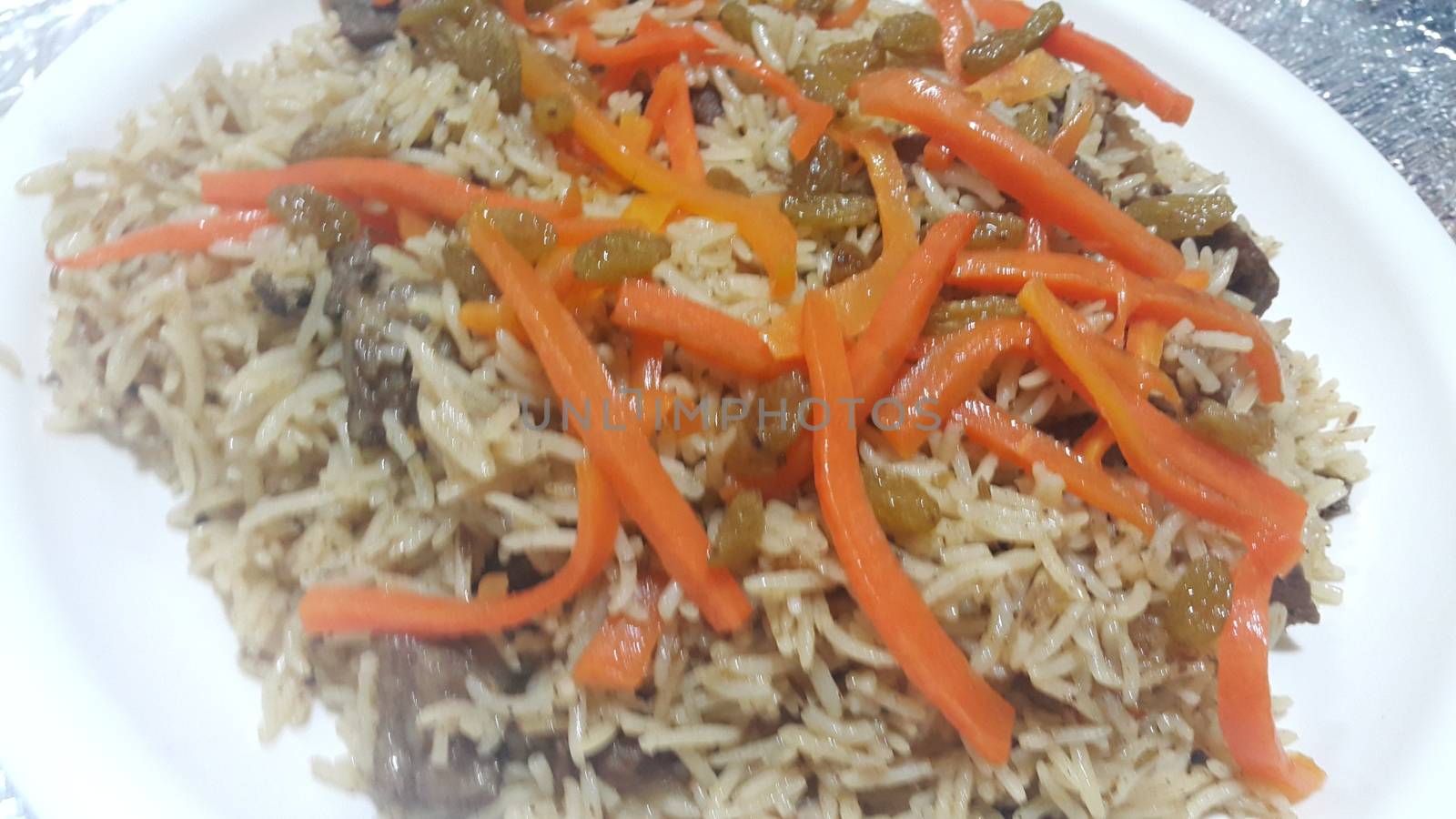 Delicious Kabuli pulao from Basmati Rice: Home made pulav with beef, carrot and dried grapes or kishmish or raisin served in a white plate