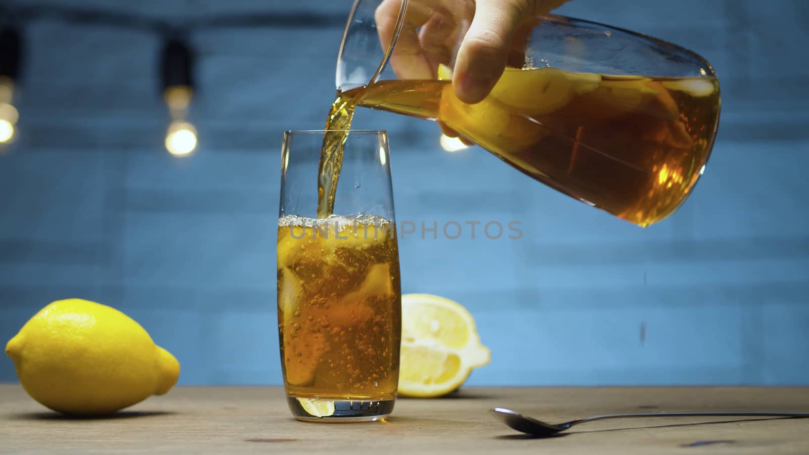 Male hand pouring ice tea into a glass by Alize