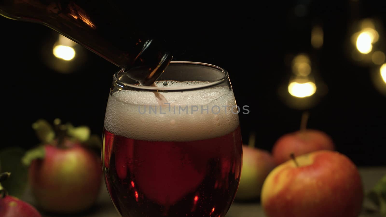 Close up delicious red apples and apple cider pouring into a glass on black background. Healthy food, vitamins, fruits