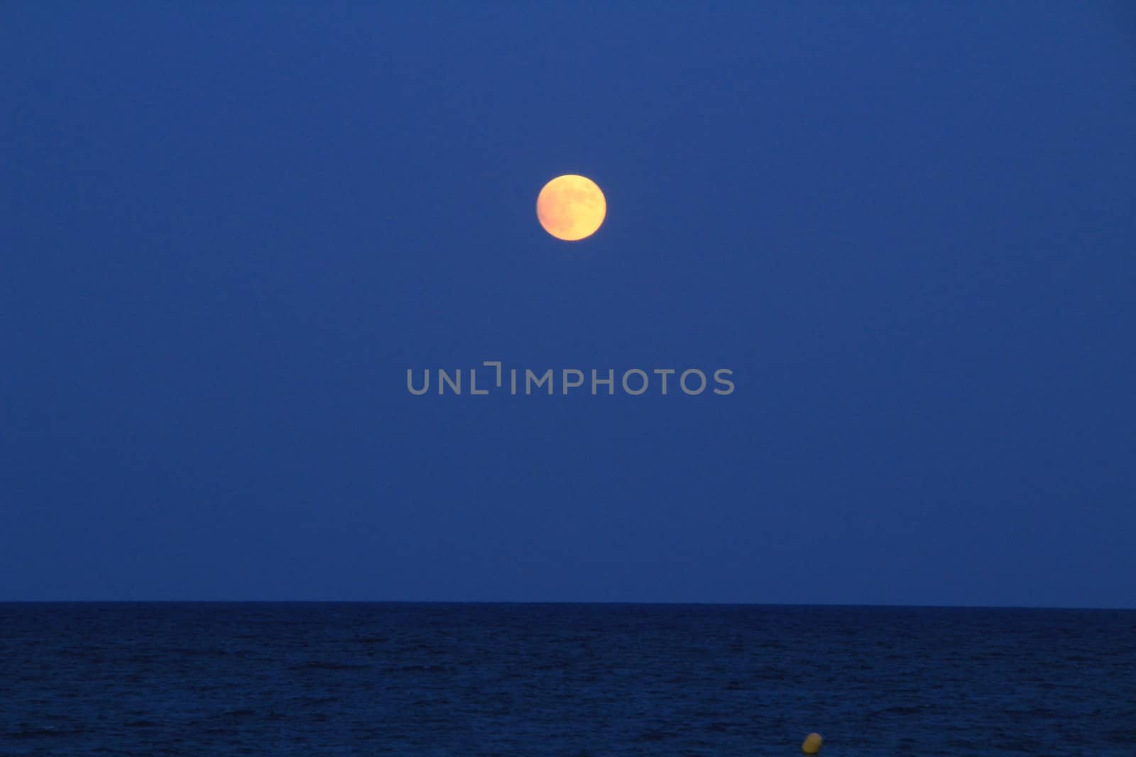 Arenales del Sol Beach in Alicante, Spain, at dusk with a full moon