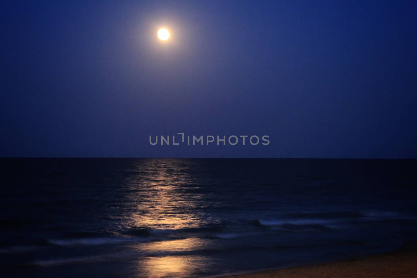 Arenales del Sol Beach in Alicante, Spain, at dusk with a full moon