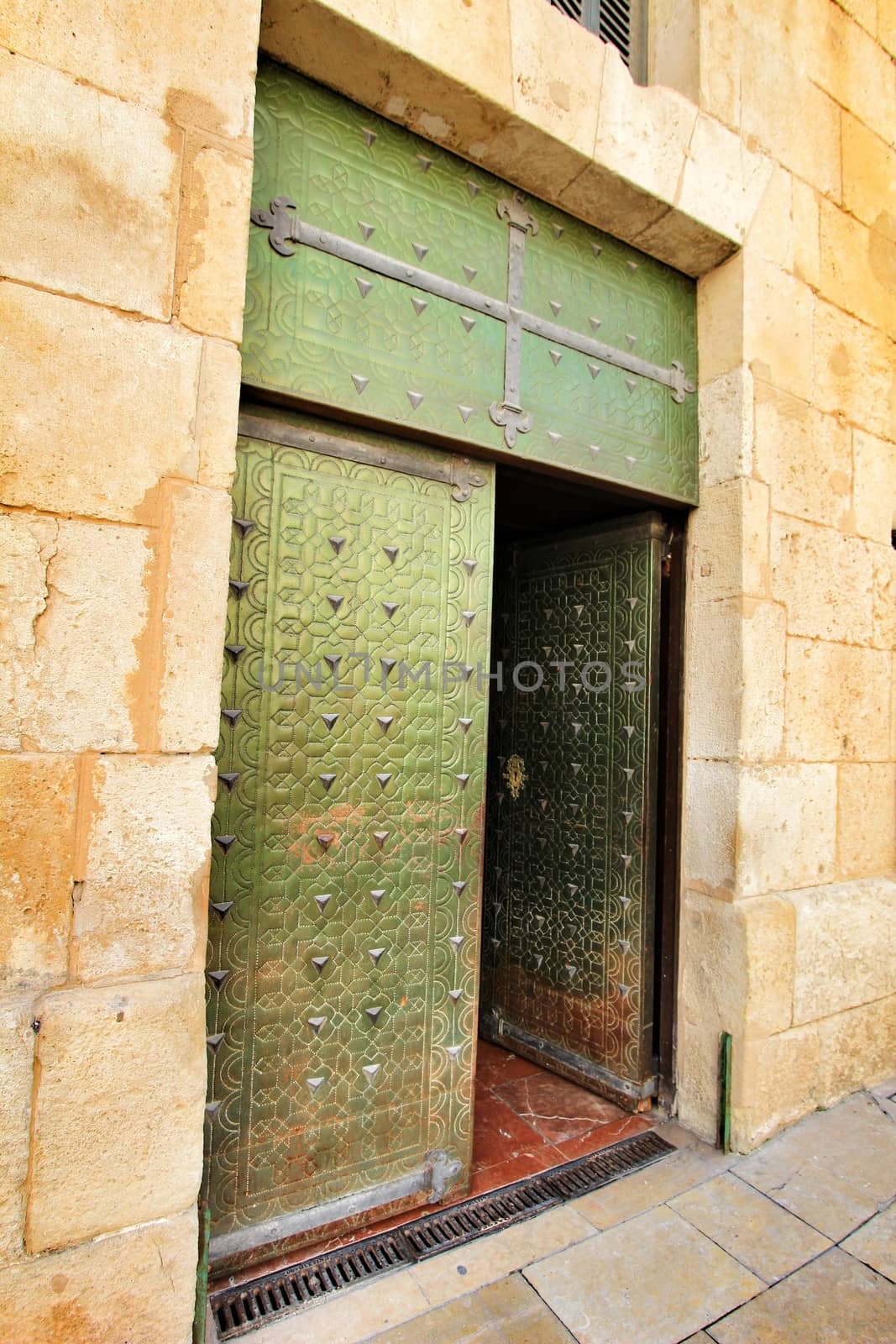 Old and colorful green wooden door with iron details by soniabonet