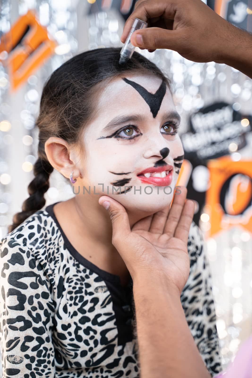 Parent helping her daughter to get ready for Halloween by doing make-up - concept of Halloween, holiday and childhood festival celebration and preparation. by lakshmiprasad.maski@gmai.com