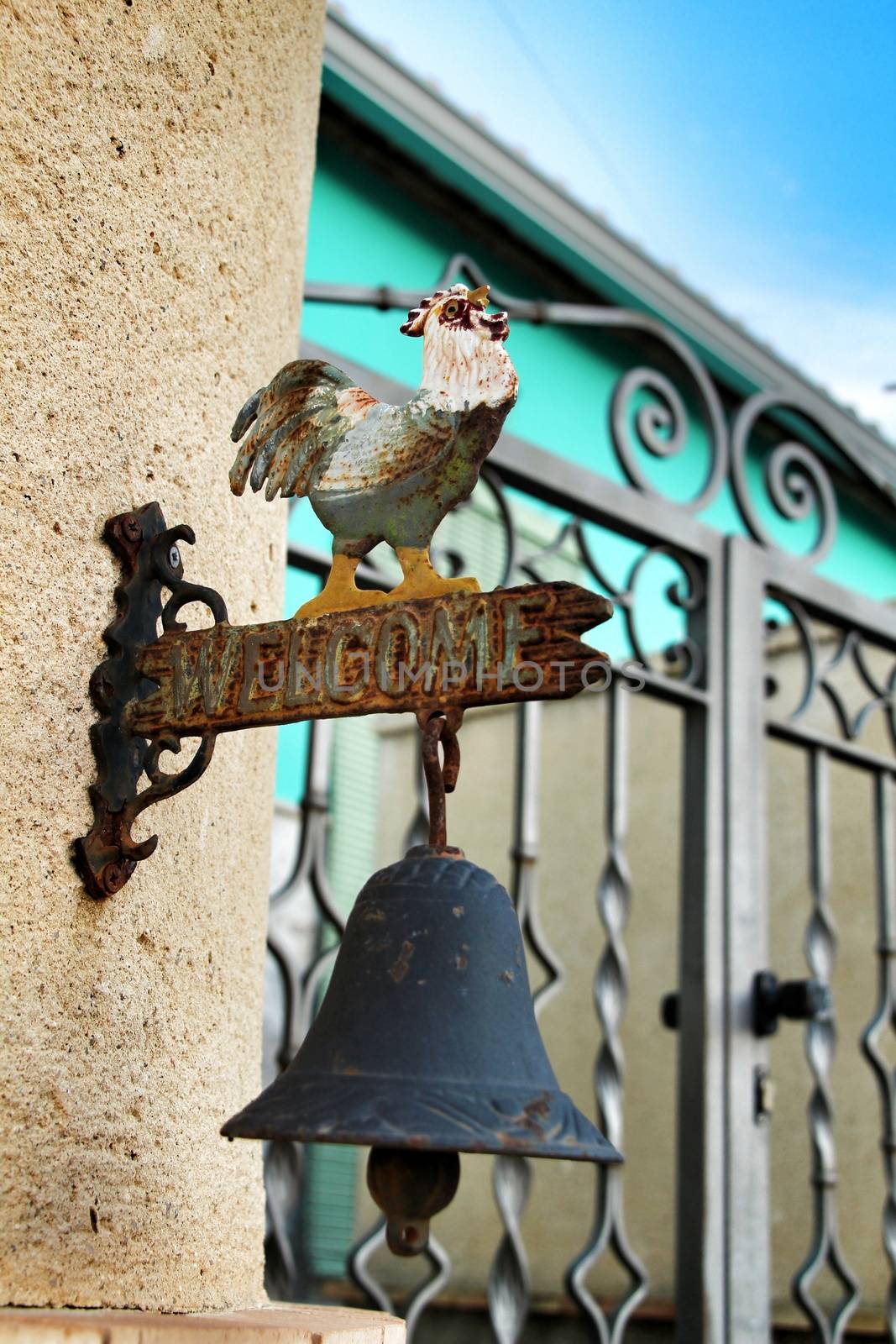 Iron bell doorbell with a rooster at the entrance of a house with a forged metal door