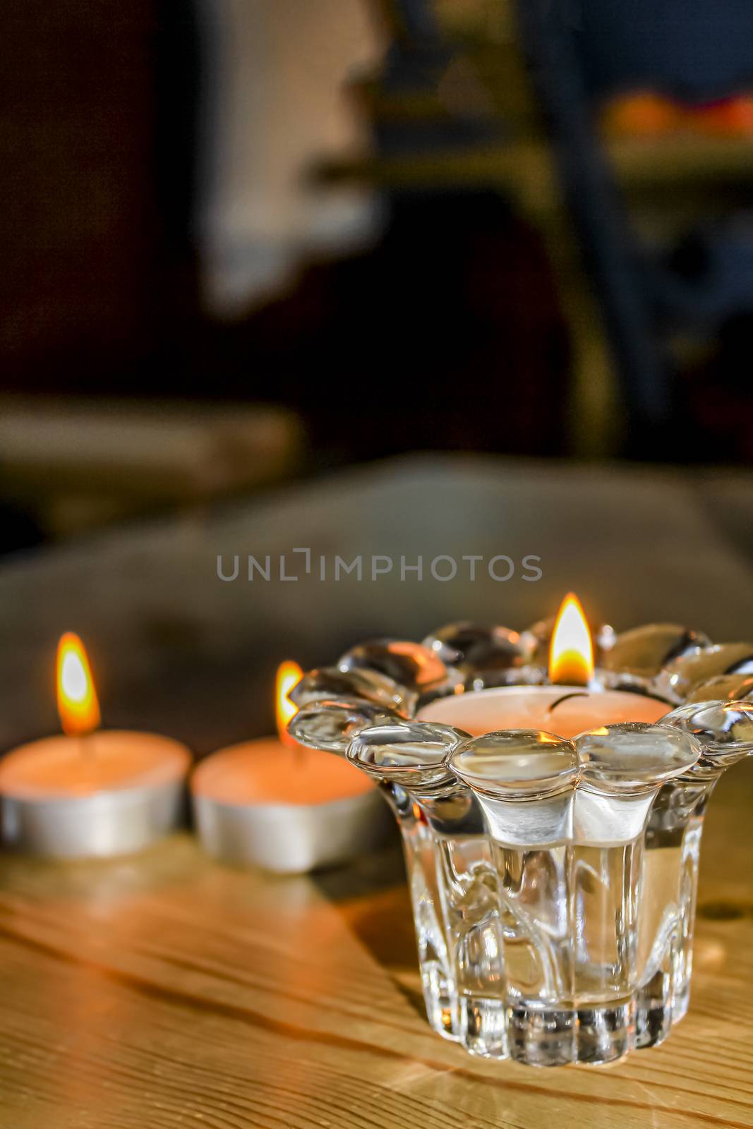 Candlelight in the glass on wooden table in Norway. by Arkadij