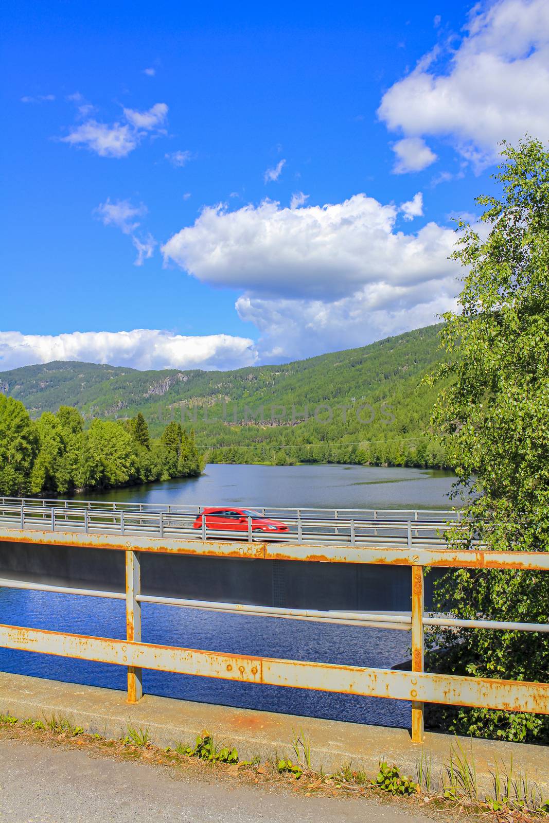 Car drives on bridge over a river, beautiful Norway landscape. by Arkadij