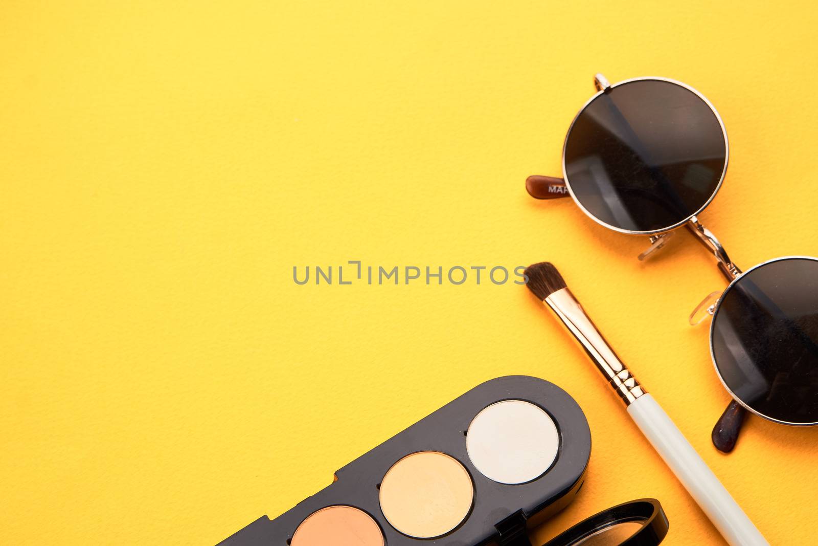 Eyeshadows on a yellow background professional cosmetics makeup brushes soft sponge fashion glasses. High quality photo