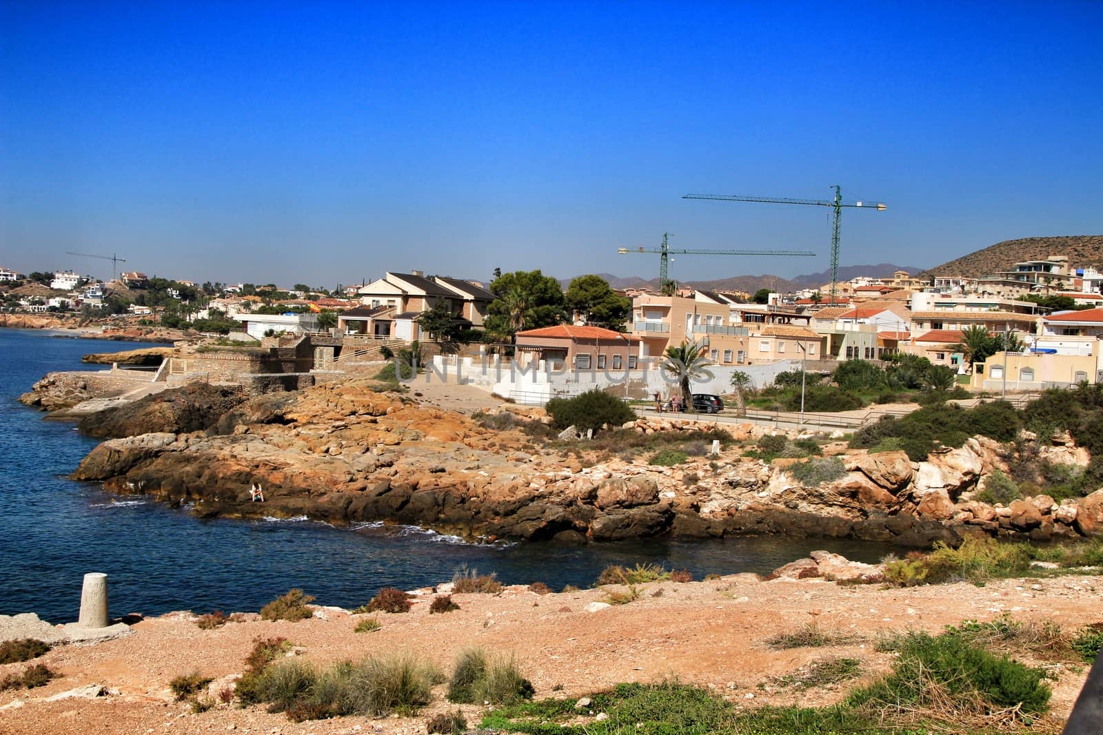 Beautiful beach with boulders, cliffs and mountains in Isla Plana village in Cartagena, Murcia, Spain in a sunny day