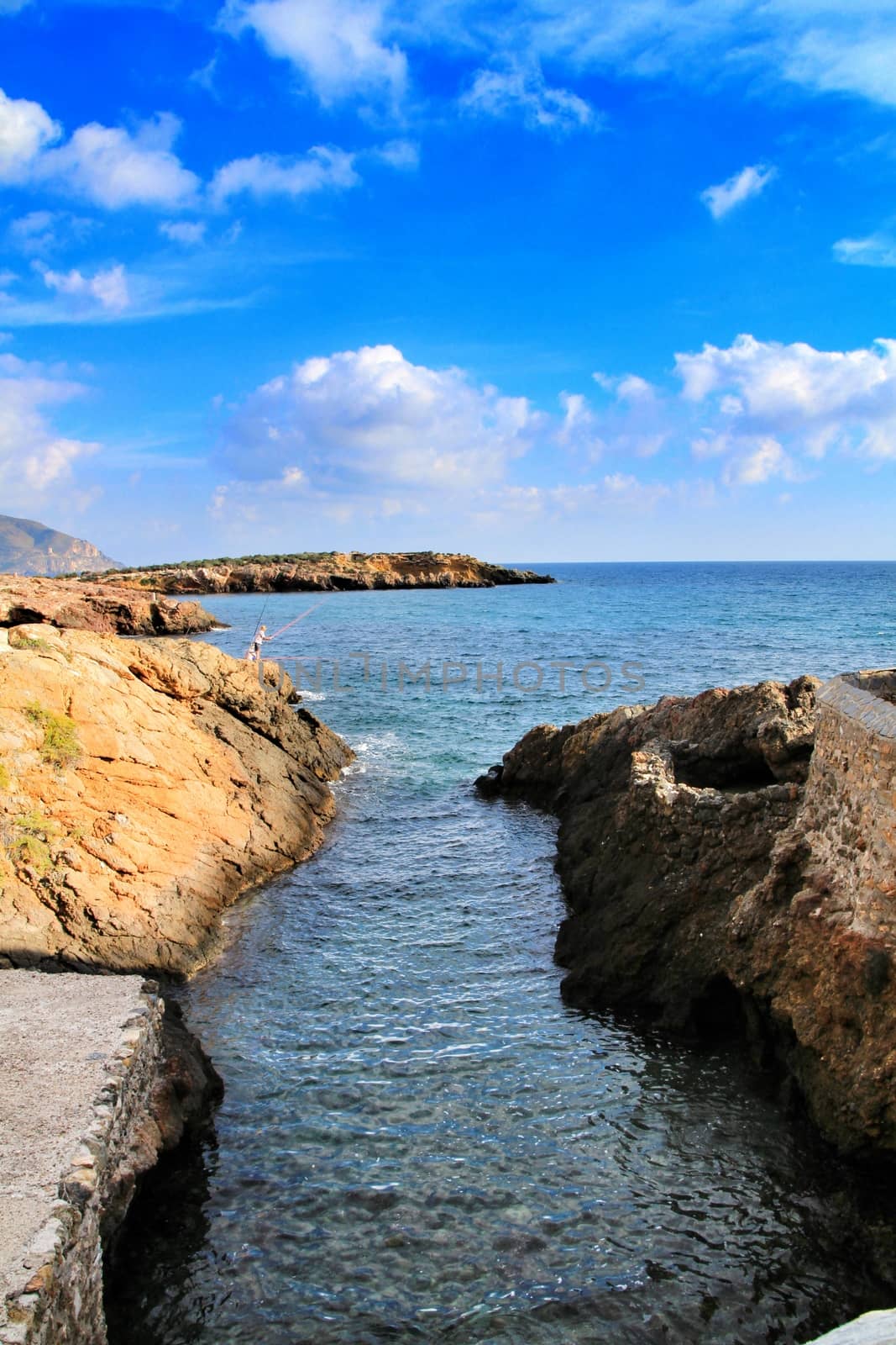 Beautiful beach with boulders, cliffs and mountains in Isla Plana village in Cartagena, Murcia, Spain in a sunny day