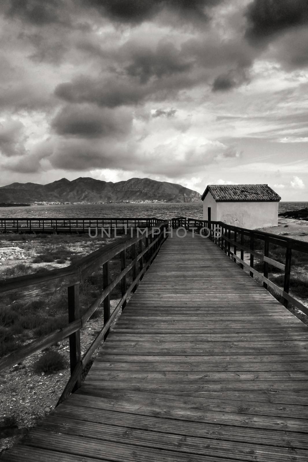 Wooden boardwalk along the beach in a stormy day in Isla Plana village in Cartagena, Murcia, Spain
