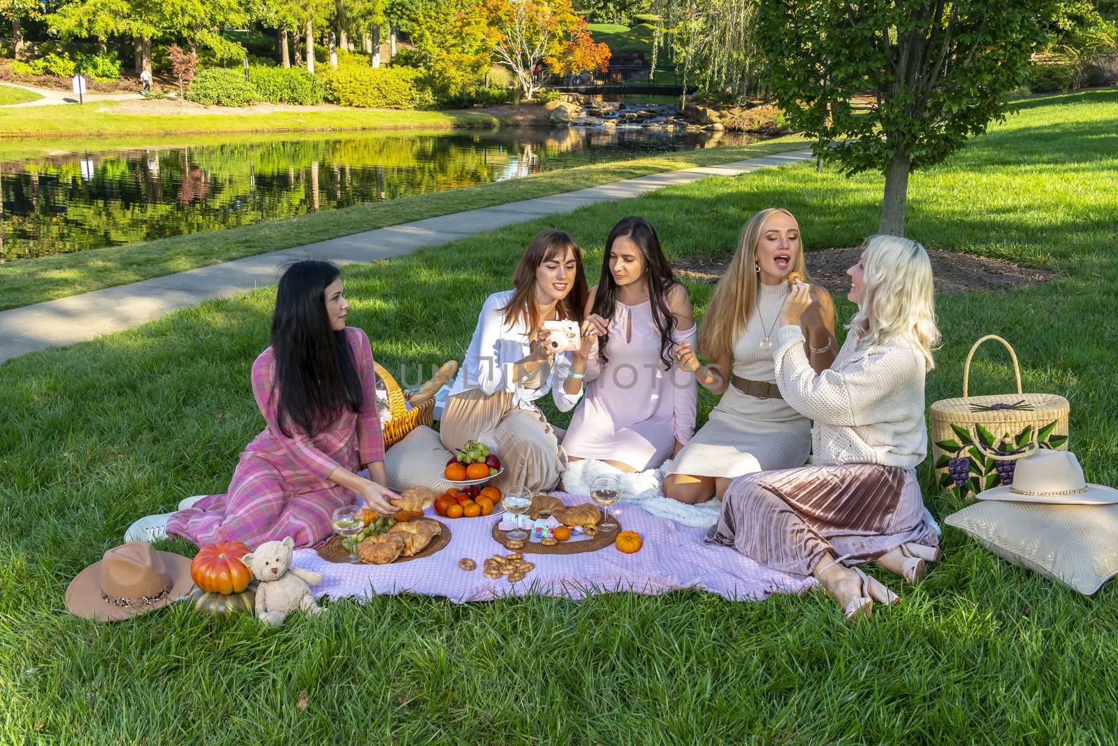 A group of beautiful women enjoy a picnic on a fall day outdoors