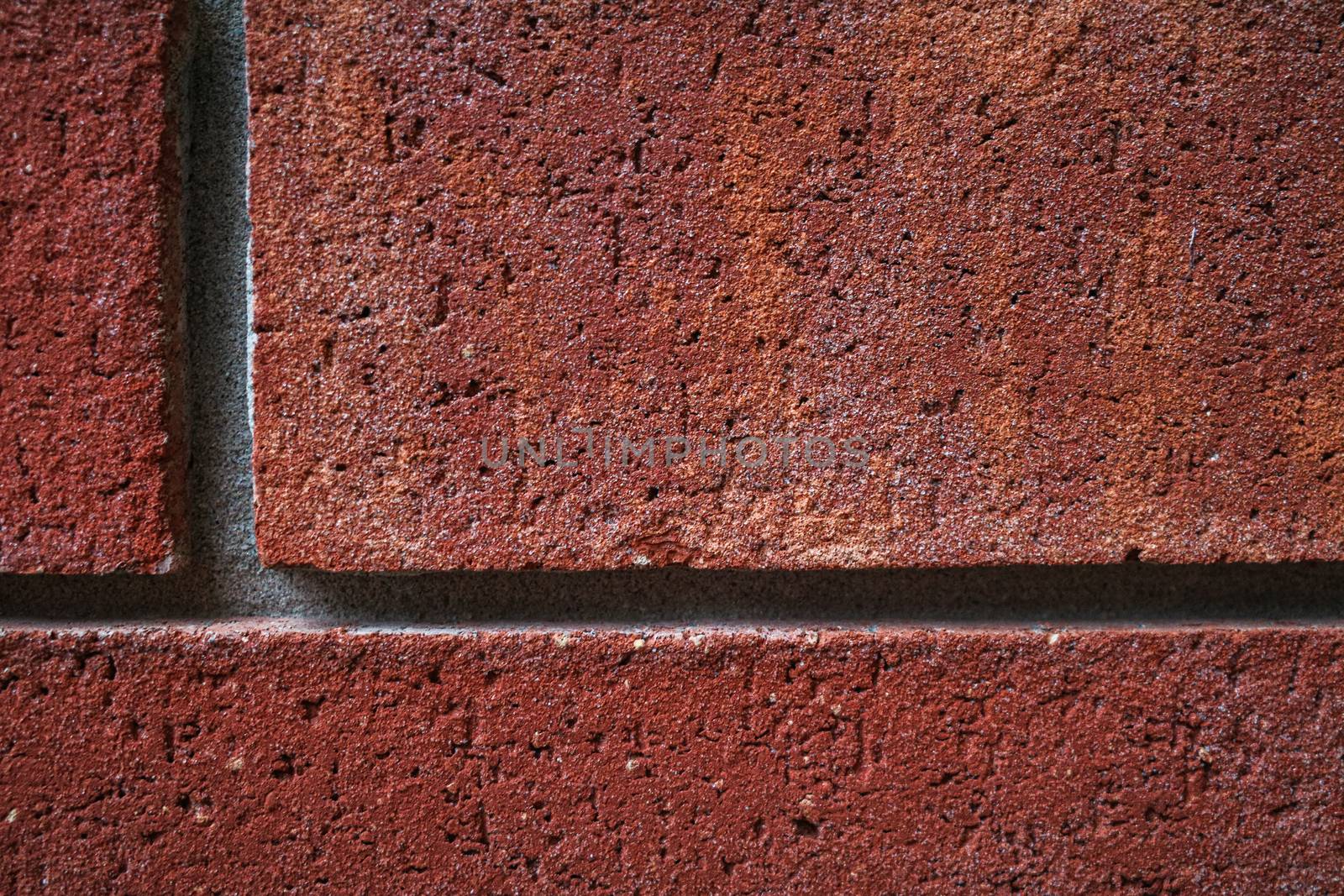 A landscape-orientation close-up image of red bricks in a wall shows texture, detail and perpendicular lines.