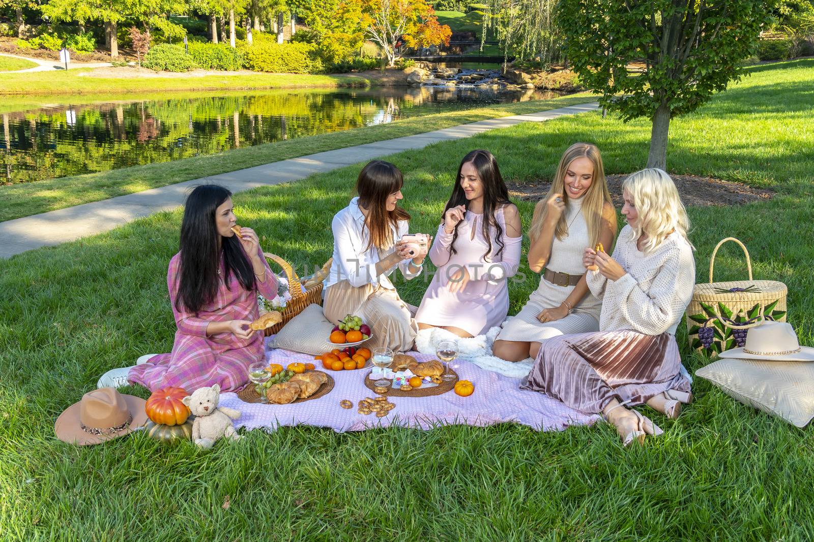A group of beautiful women enjoy a picnic on a fall day outdoors