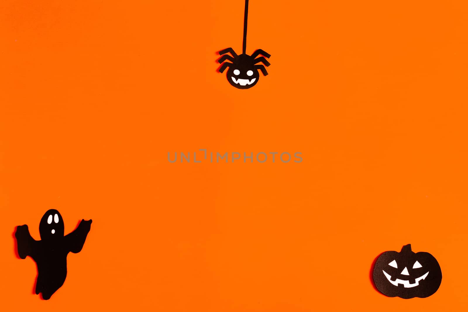 silhouettes of a Ghost, spider and pumpkin made of black paper on an orange background, Halloween concept, ready-made layout with space for text, copy space. Flat lay for your design by Pirlik