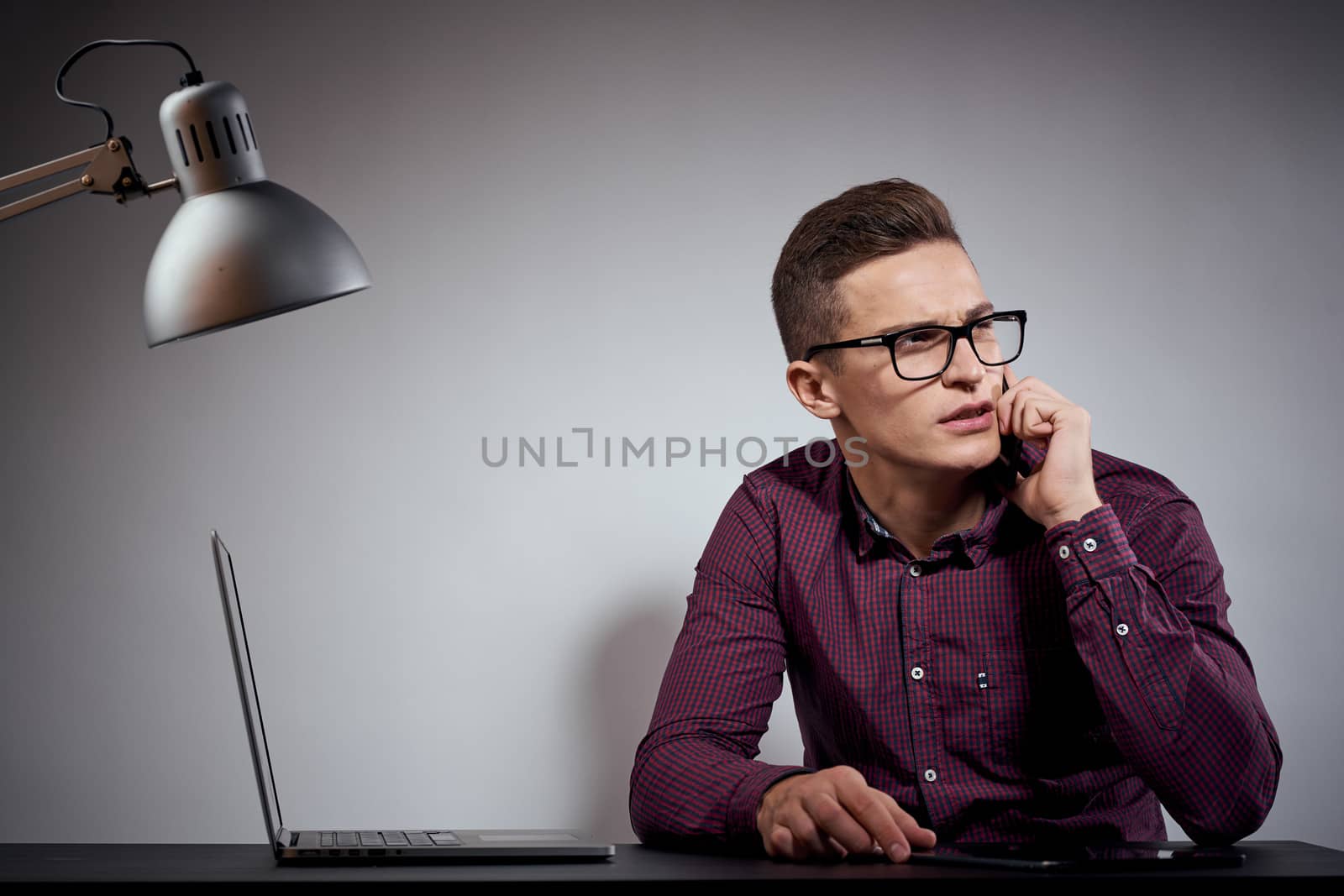 businessman in glasses and a shirt sits at a table with open laptops Coffee Space mobile phone. High quality photo