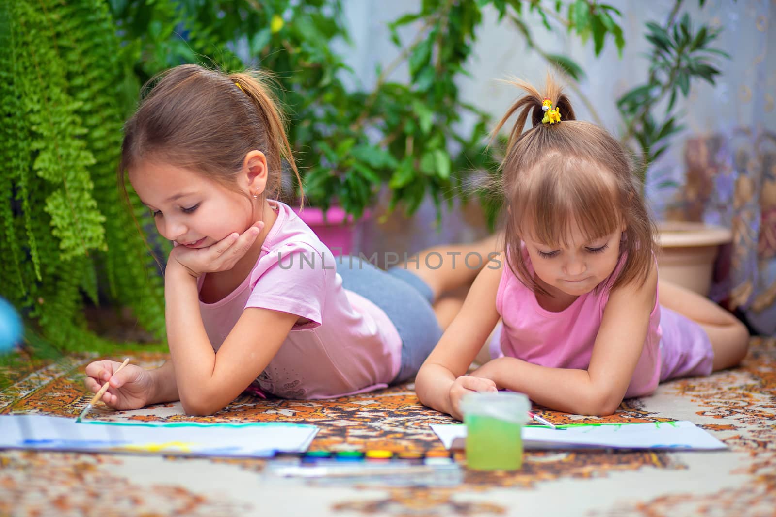 Two girls paint with paints lying on the floor at home or in kindergarten. Children's creativity by borisenkoket