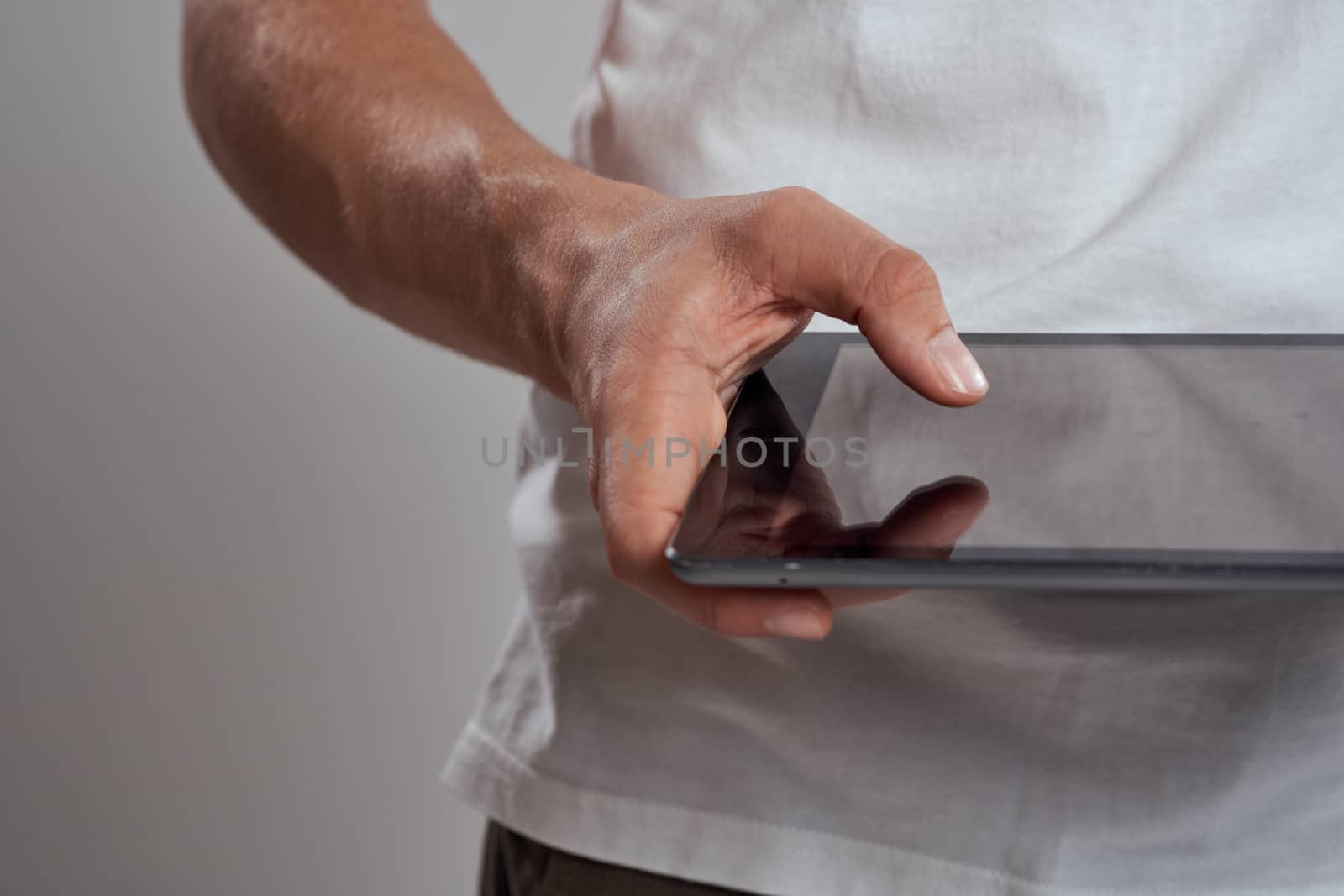 Tablet with a touch screen on a light background male hands white t-shirt cropped view by SHOTPRIME