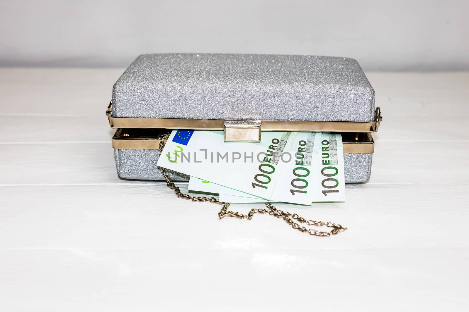 Glittery silver clutch bag with money isolated on white background with copy space.