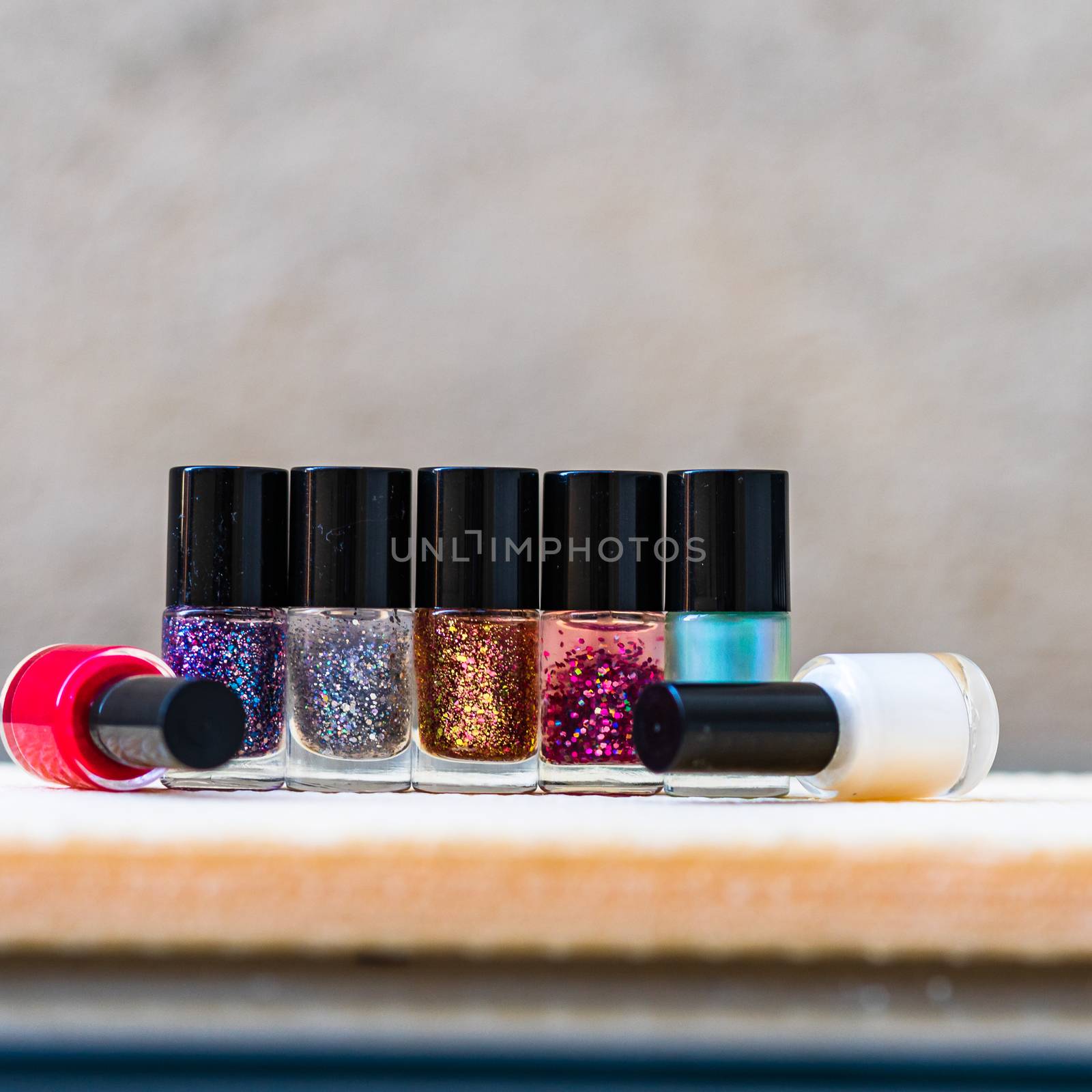 Close up photo of colorful, bright and glittery nail polish bott by vladispas
