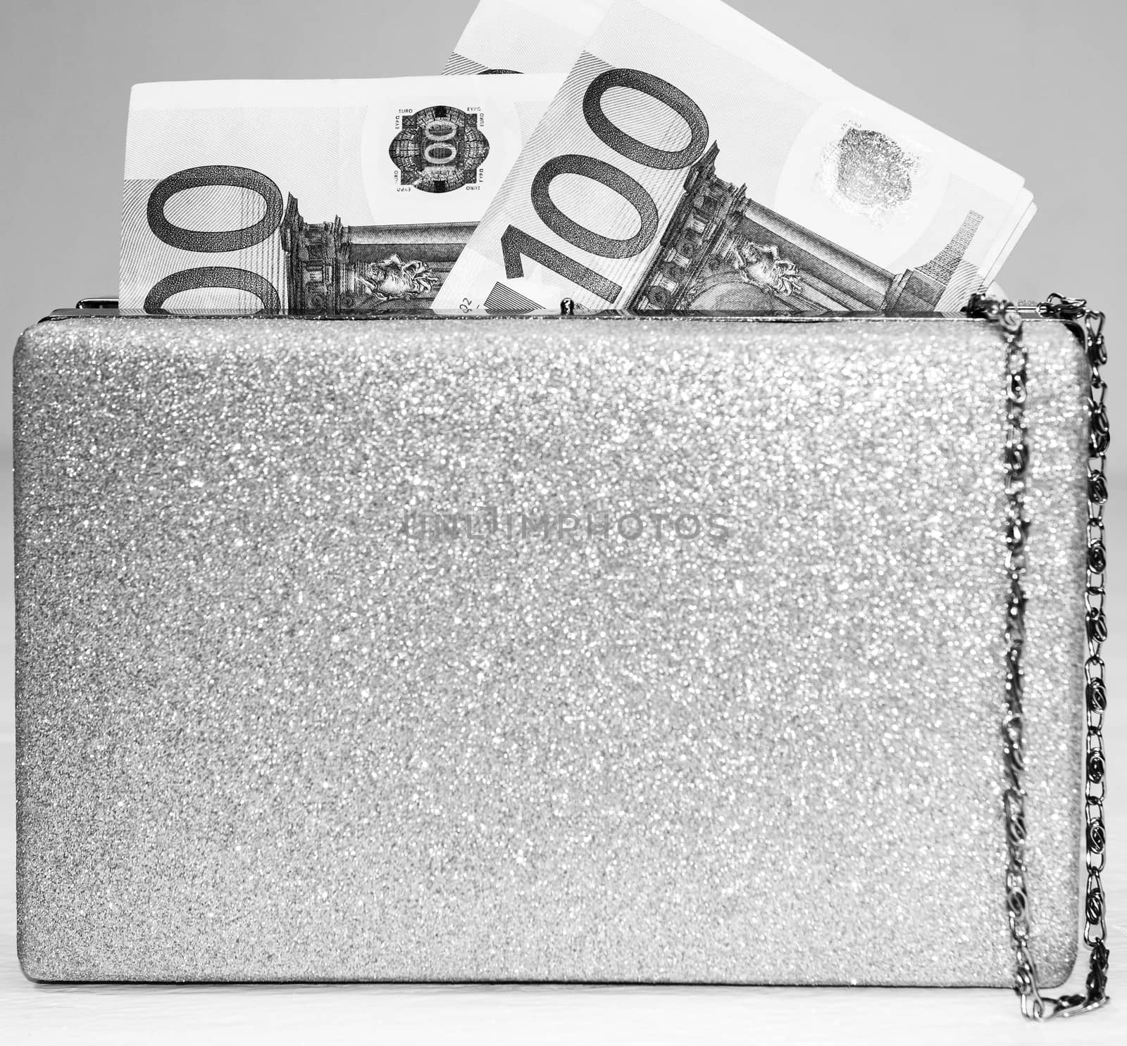 Glittery silver clutch bag with money isolated on white background with copy space.