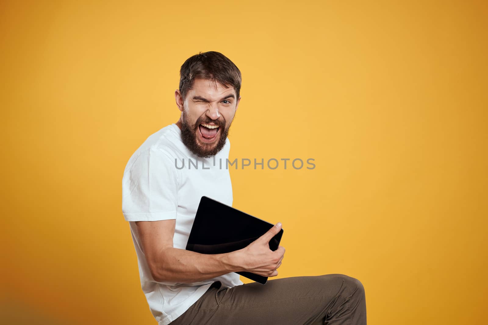 Man with a tablet on a yellow background in a white t-shirt new technologies businessman touch screen touchpad by SHOTPRIME