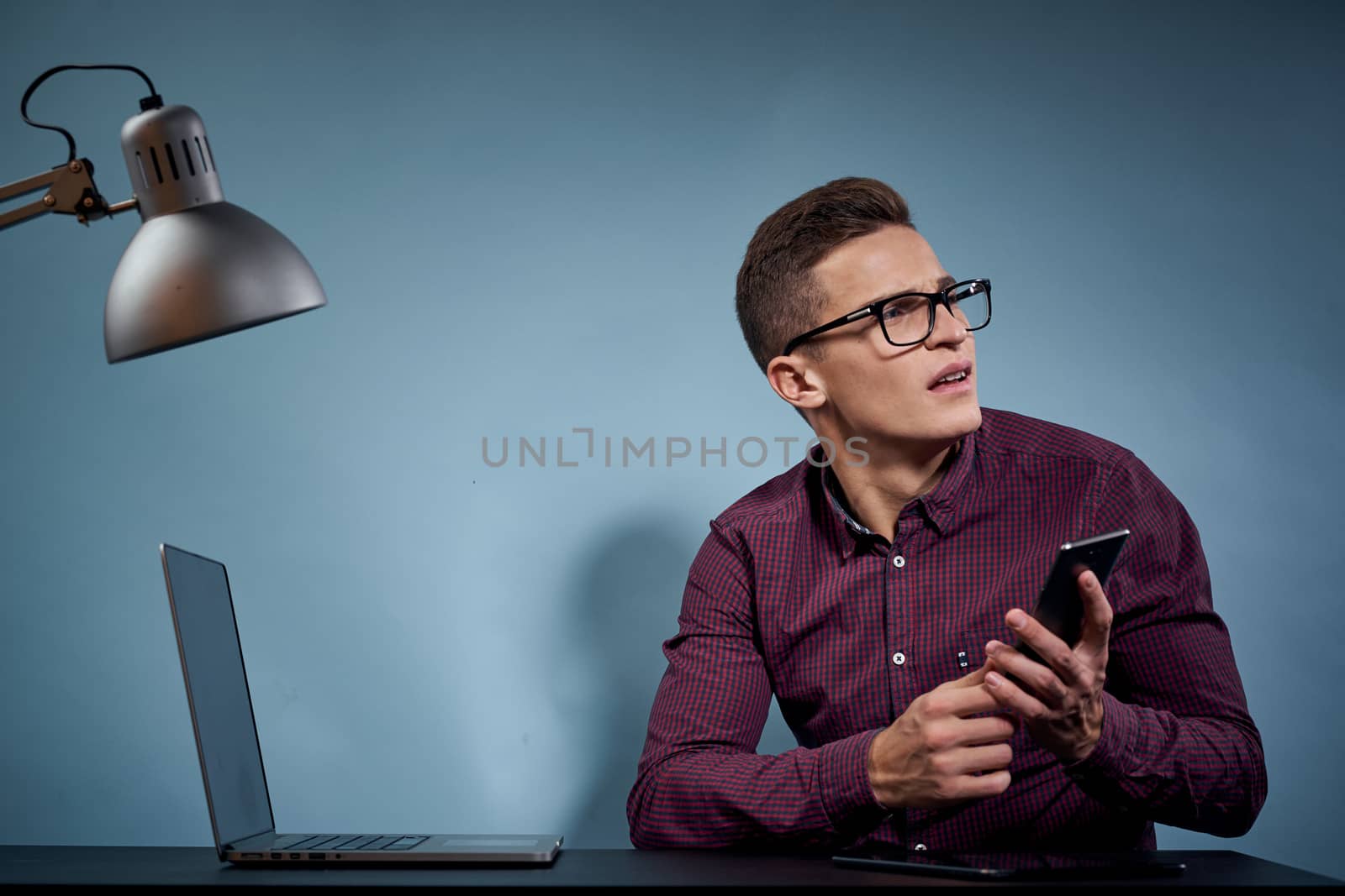 A man in a shirt with a laptop at the table is a manager in the office and a lamp cabinet model. High quality photo