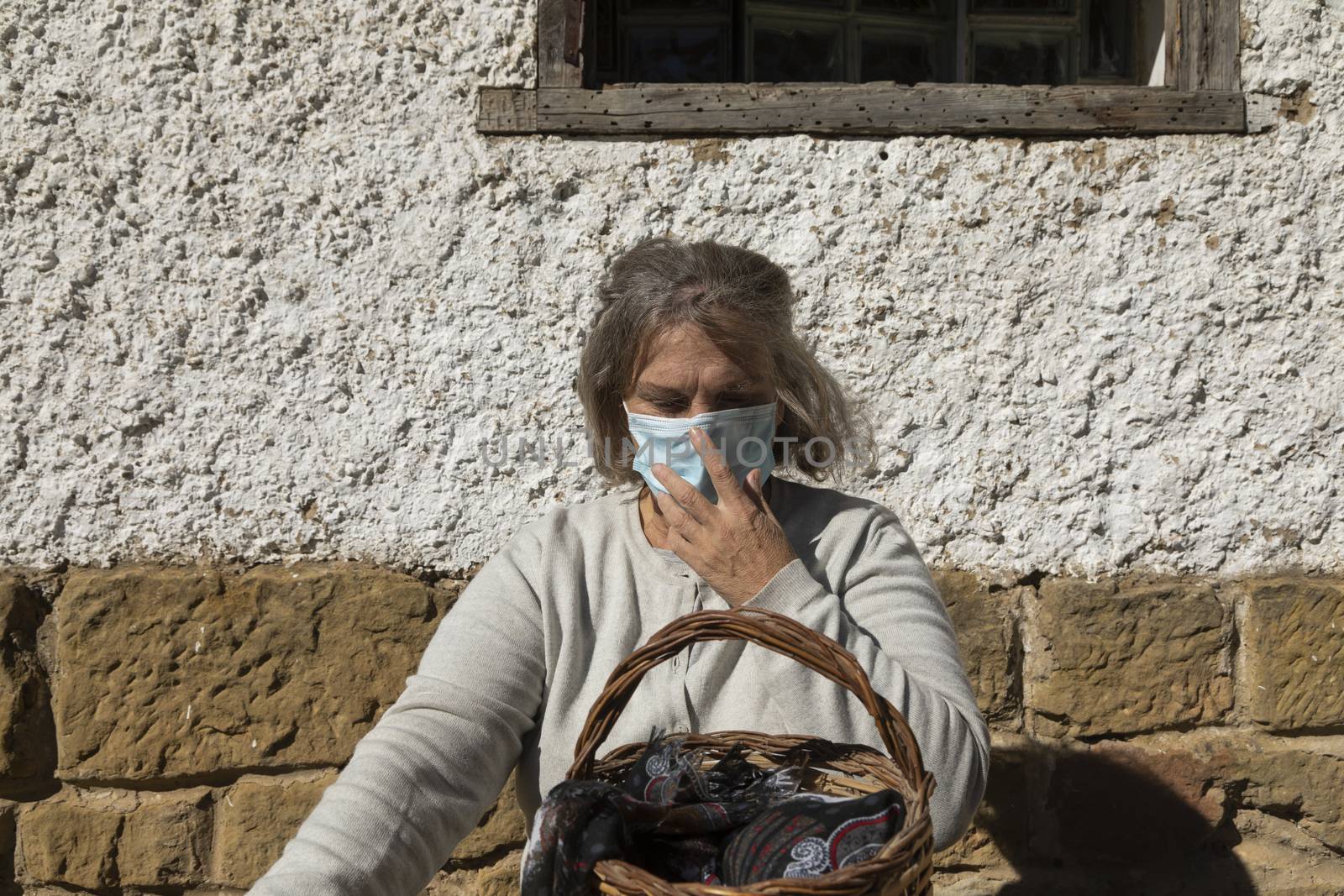A senior woman, correctly adjusts her protective face mask, Spain by alvarobueno