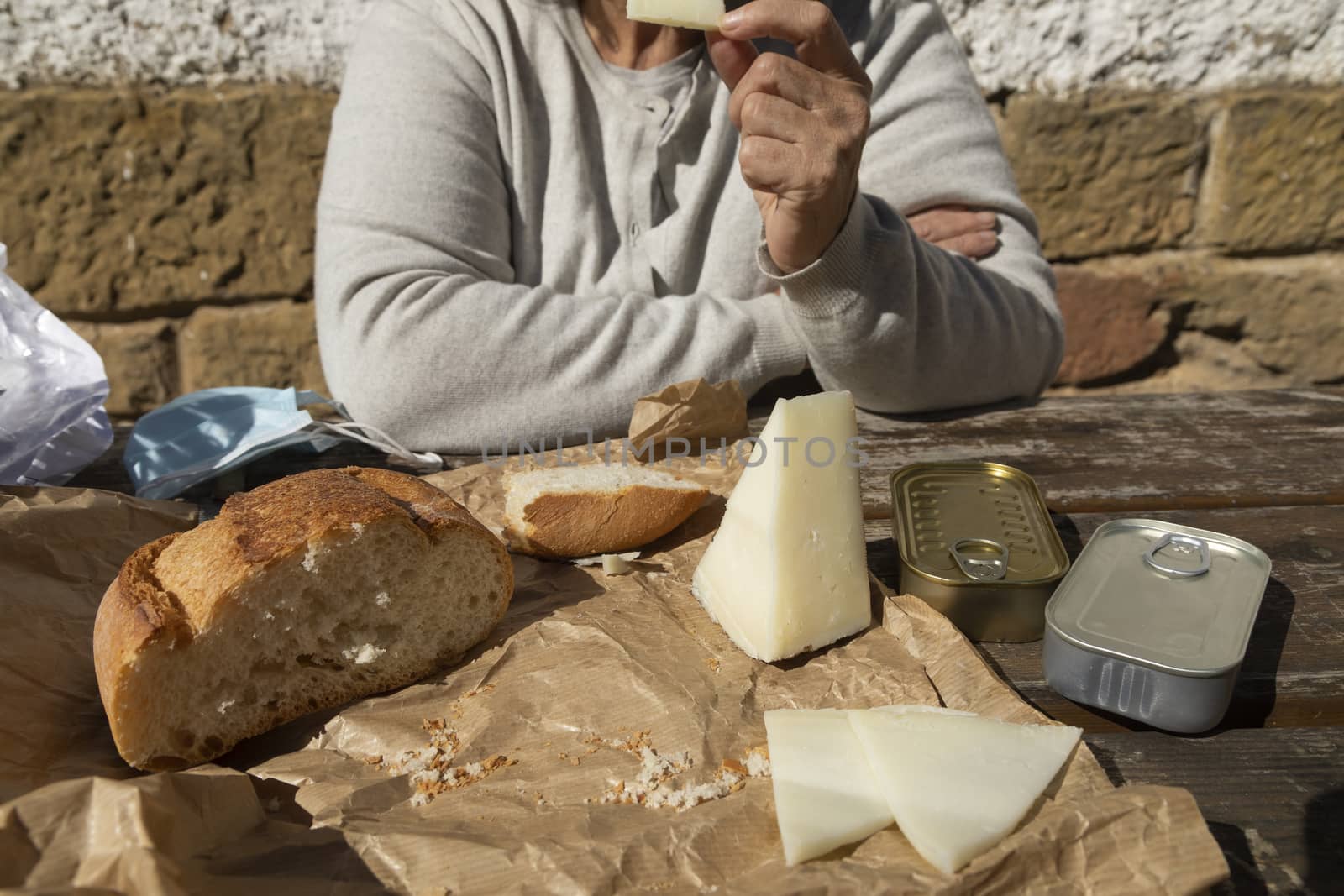 A senior woman, eats slices of goat cheese, Spain by alvarobueno